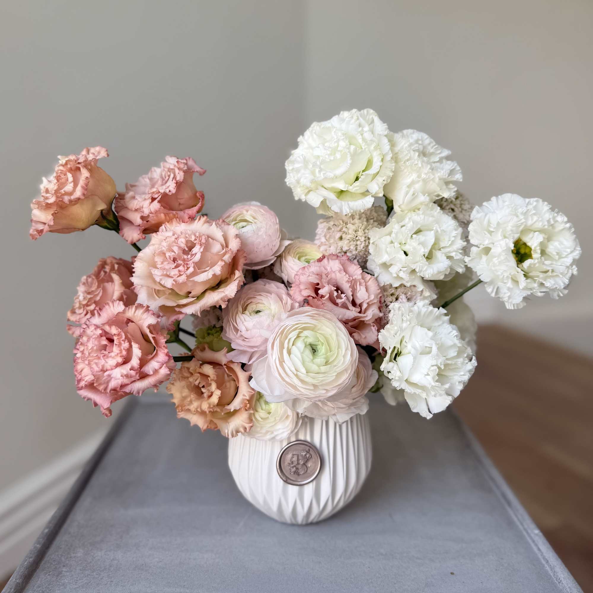 Pink and white flowers arranged in a white vase