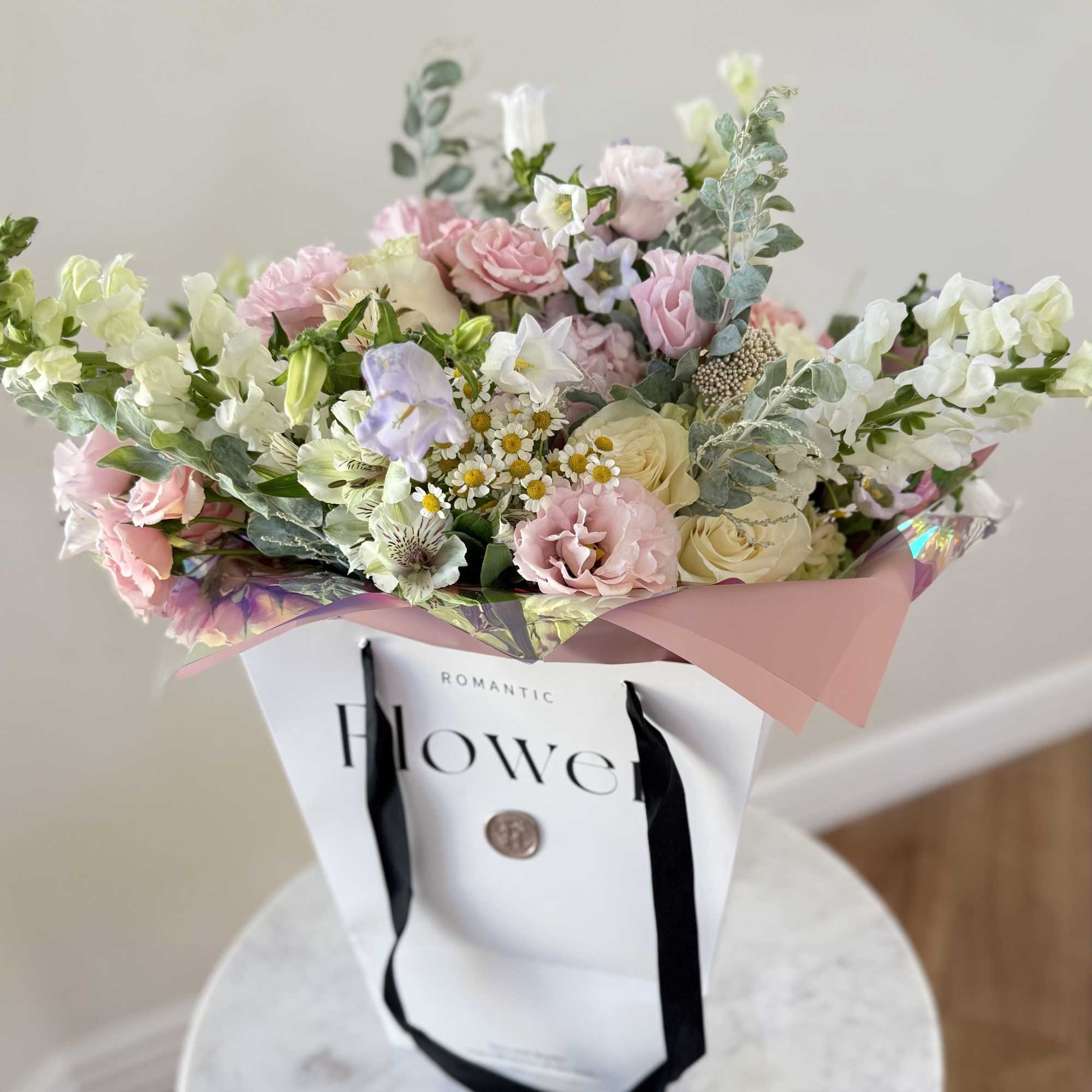 Pastel mixed bouquet in a white gift bag with black ribbons