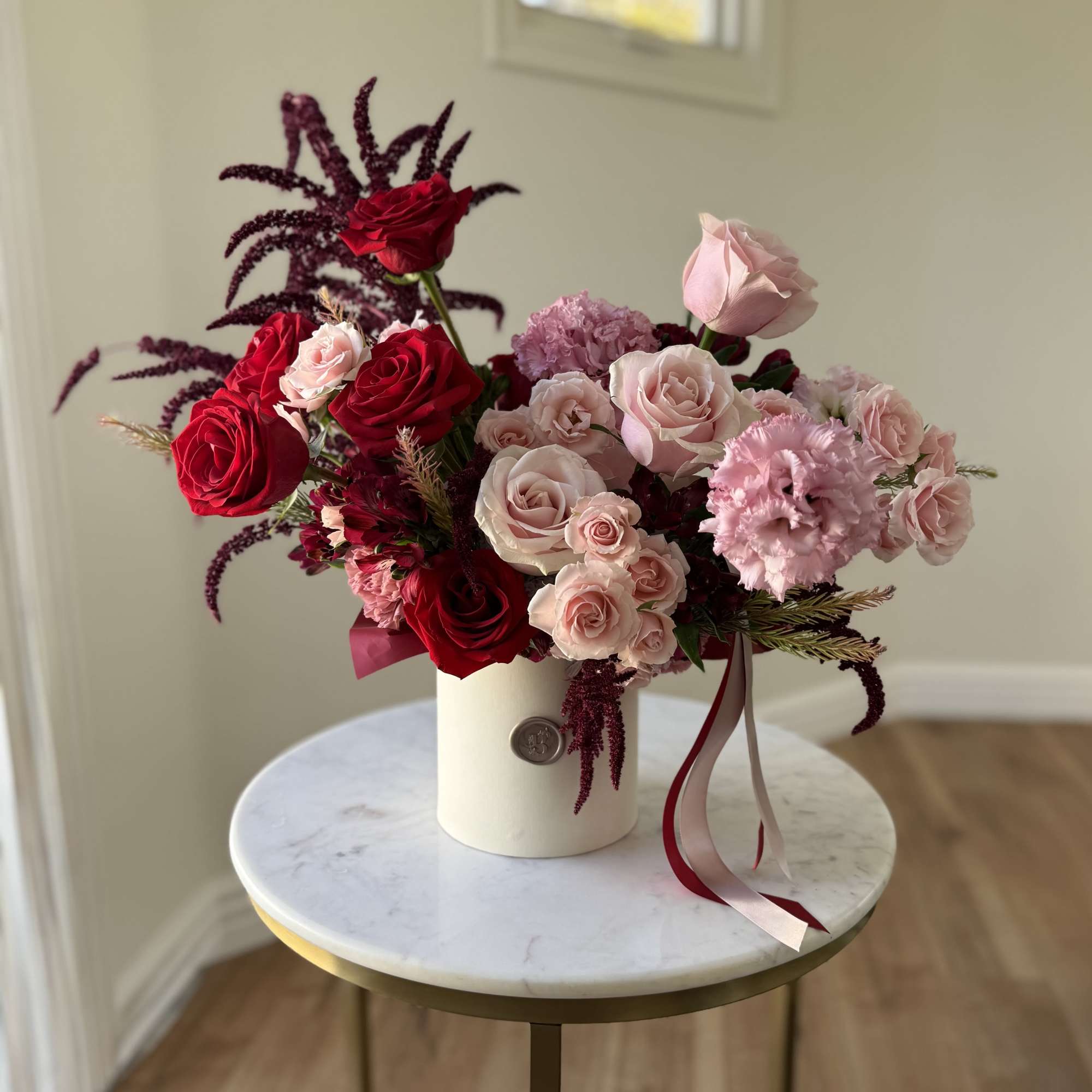 Bouquet of red and blush roses in a white cylindrical vase