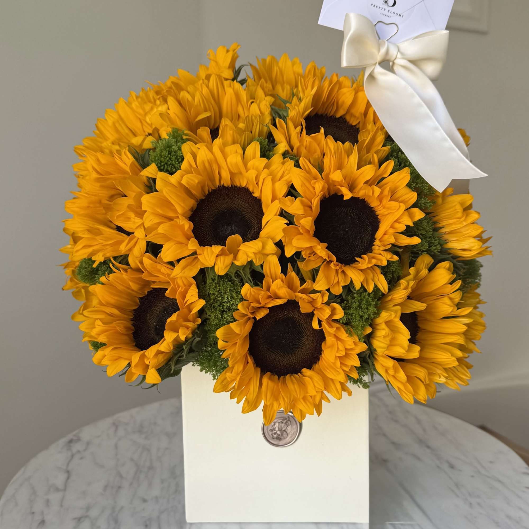 Bouquet of bright yellow sunflowers in a white gift box with a ribbon