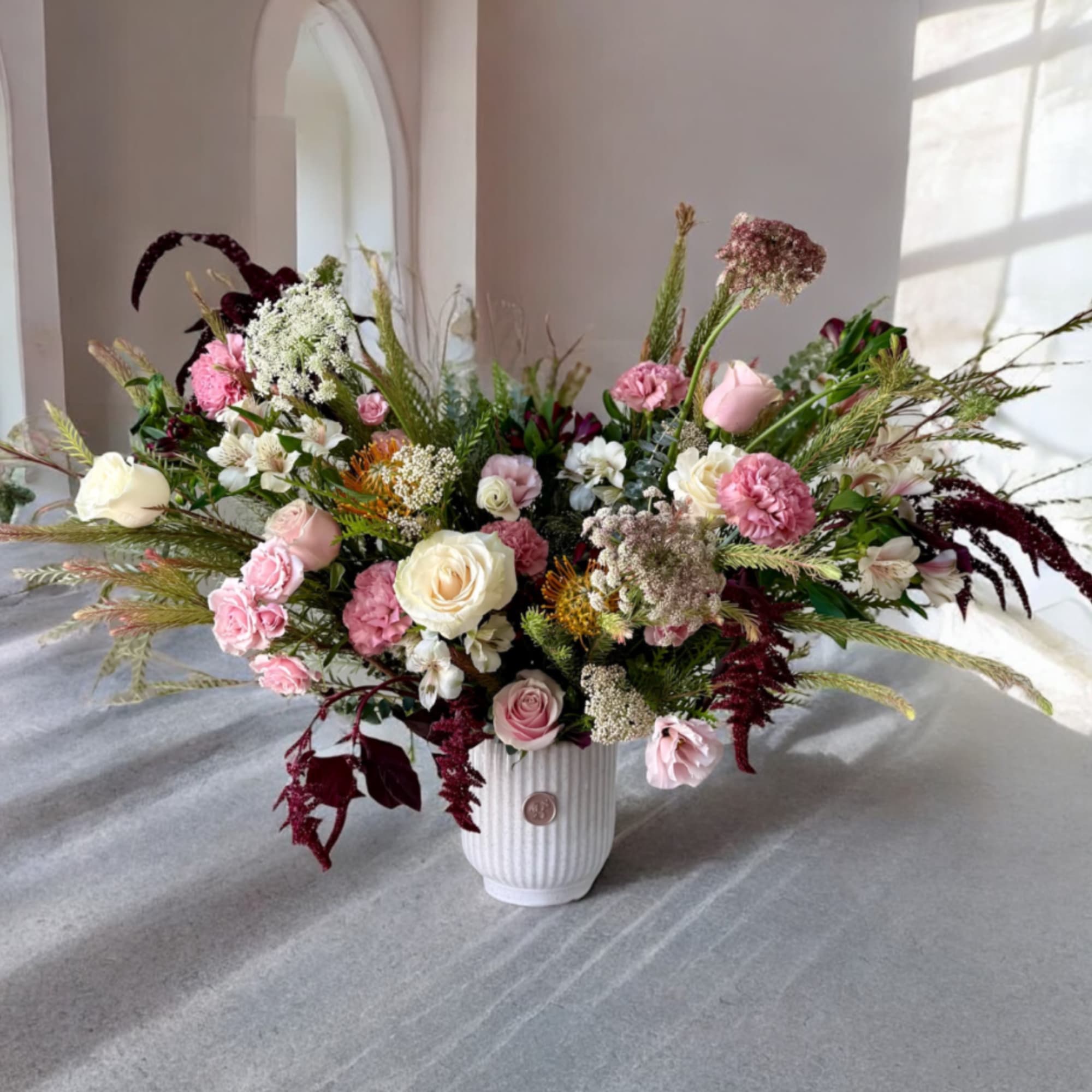 Large mixed bouquet in a white ribbed vase with pink and white blooms