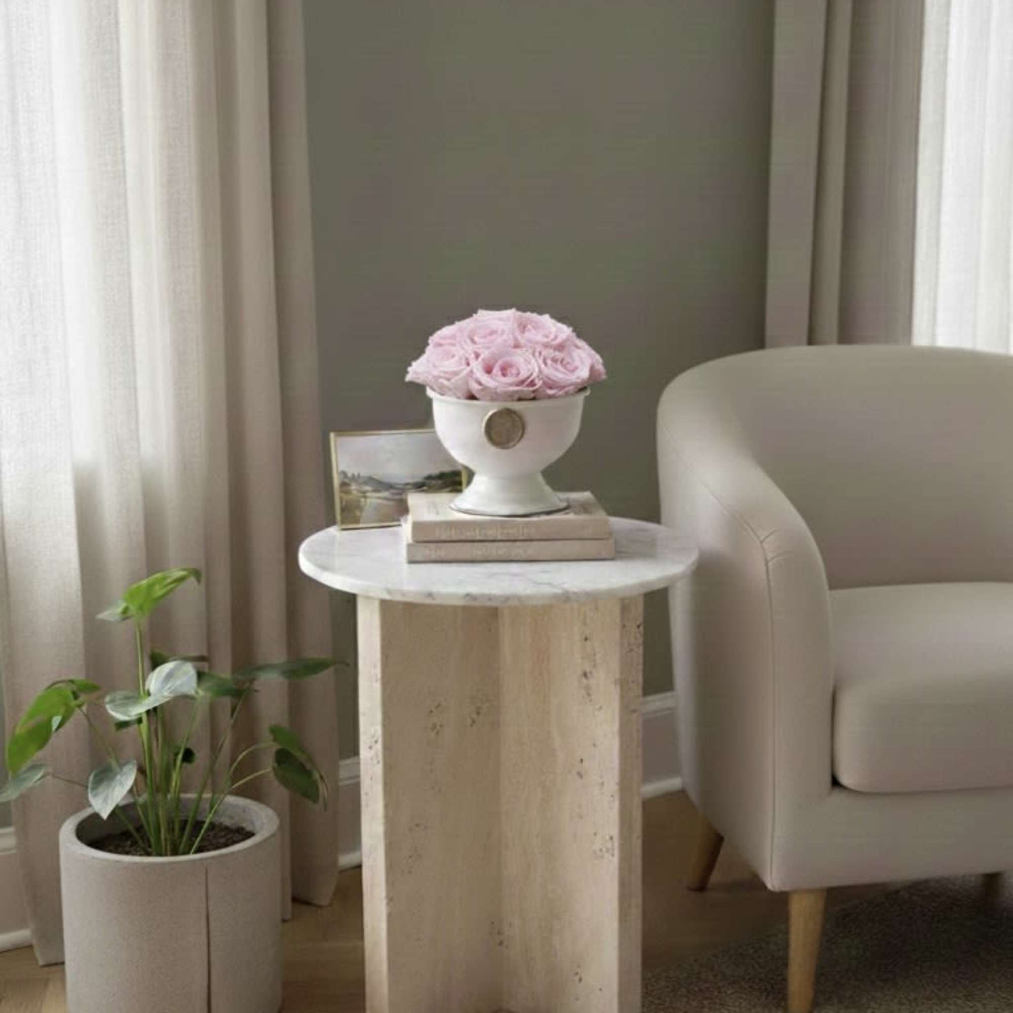 Pink roses arranged in a white urn on a small table
