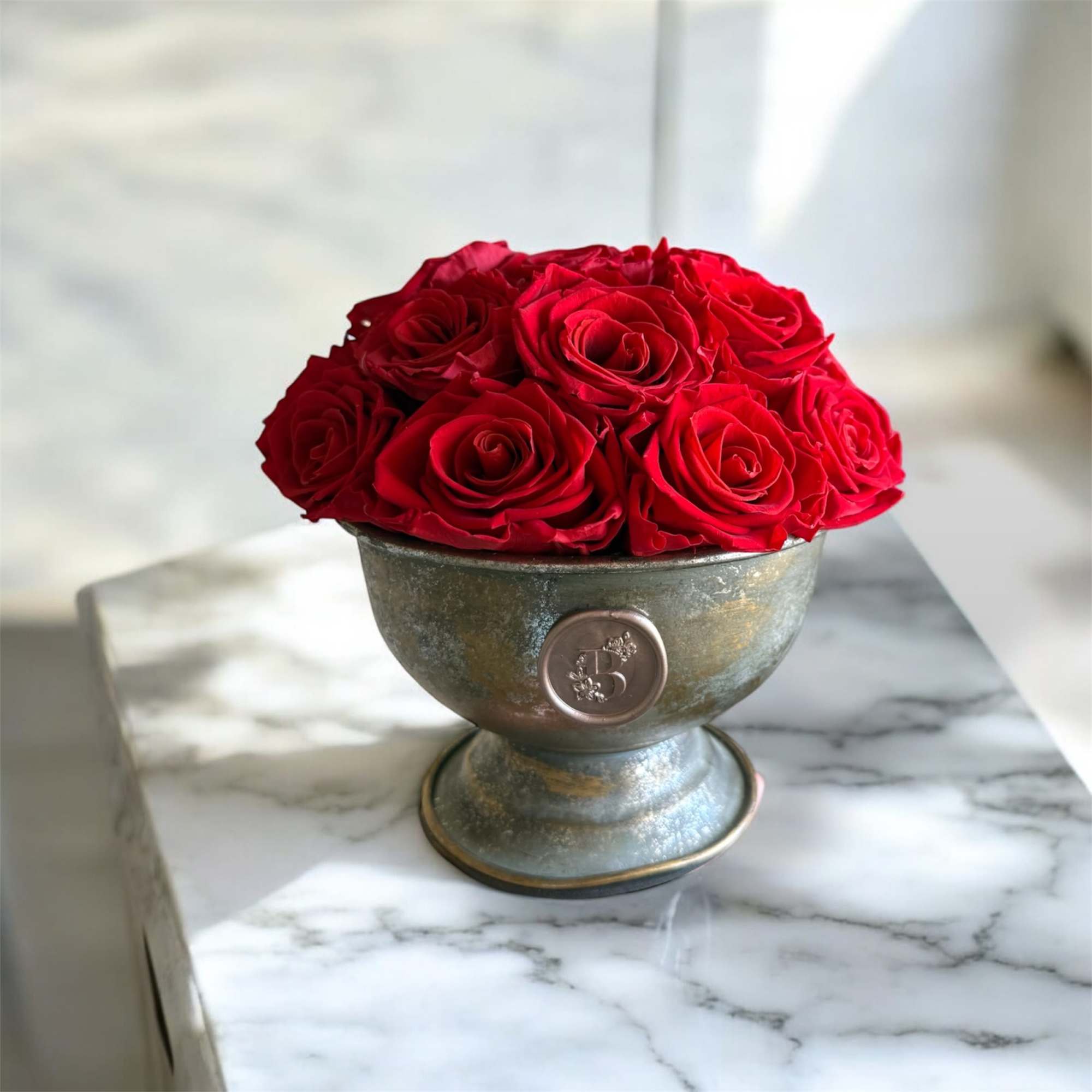 Red roses arranged in a metal pedestal bowl