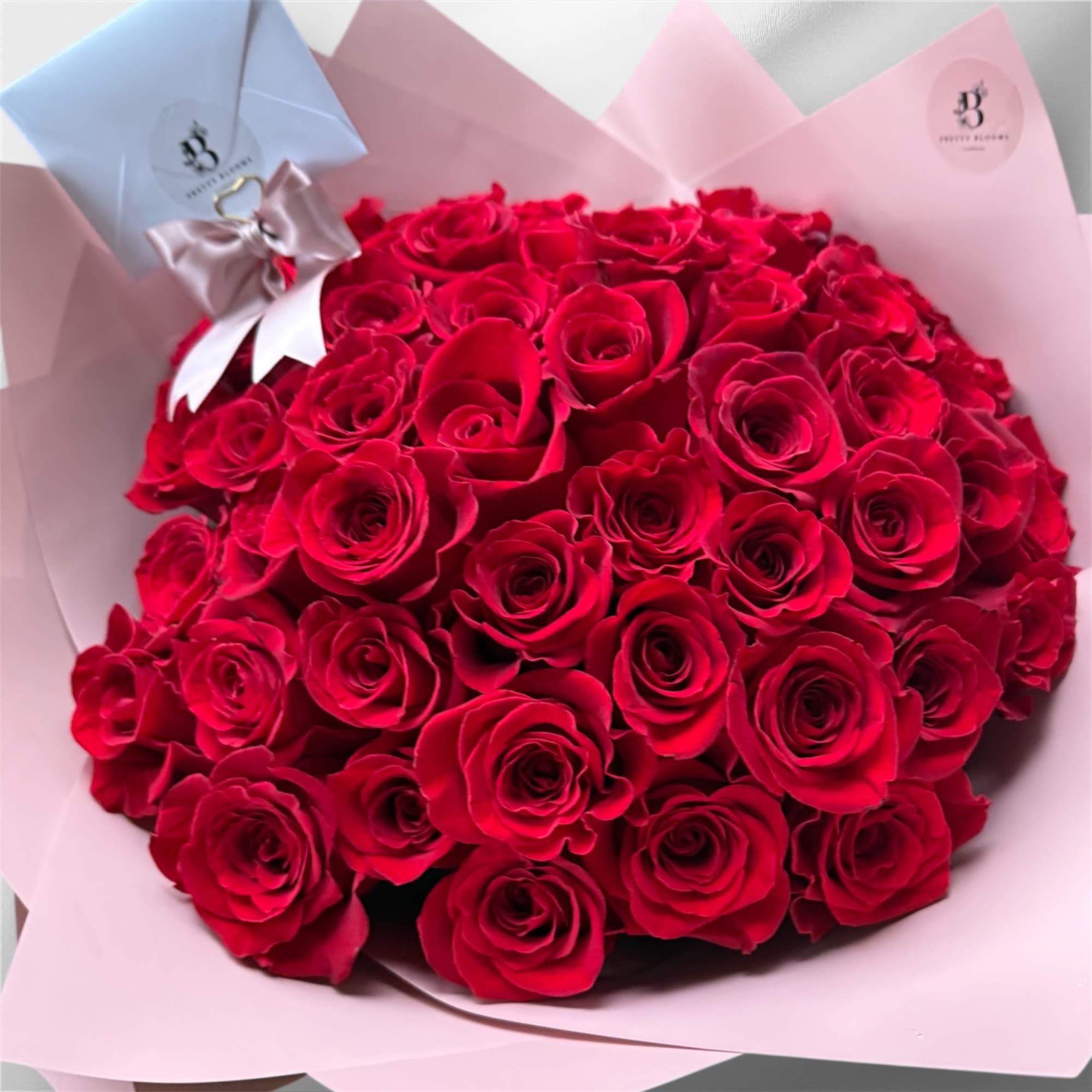 Large bouquet of red roses wrapped in pale pink paper