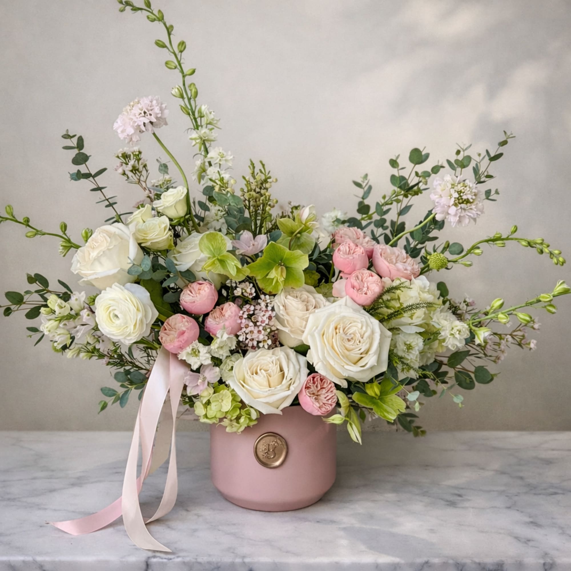 Pink and white floral arrangement in a blush vase with ribbon