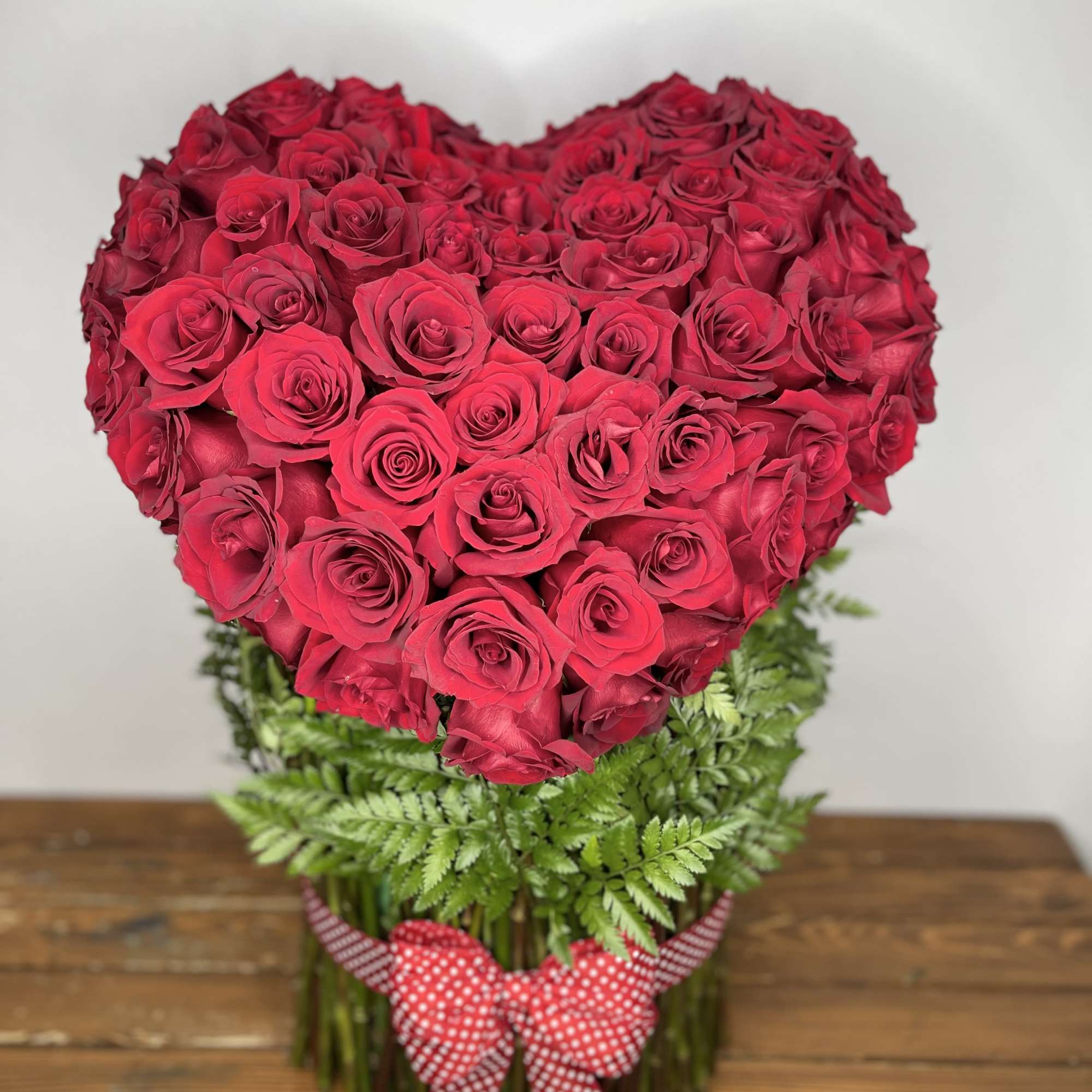 An elegant heart-shaped arrangement crafted with dozens of lush red or any