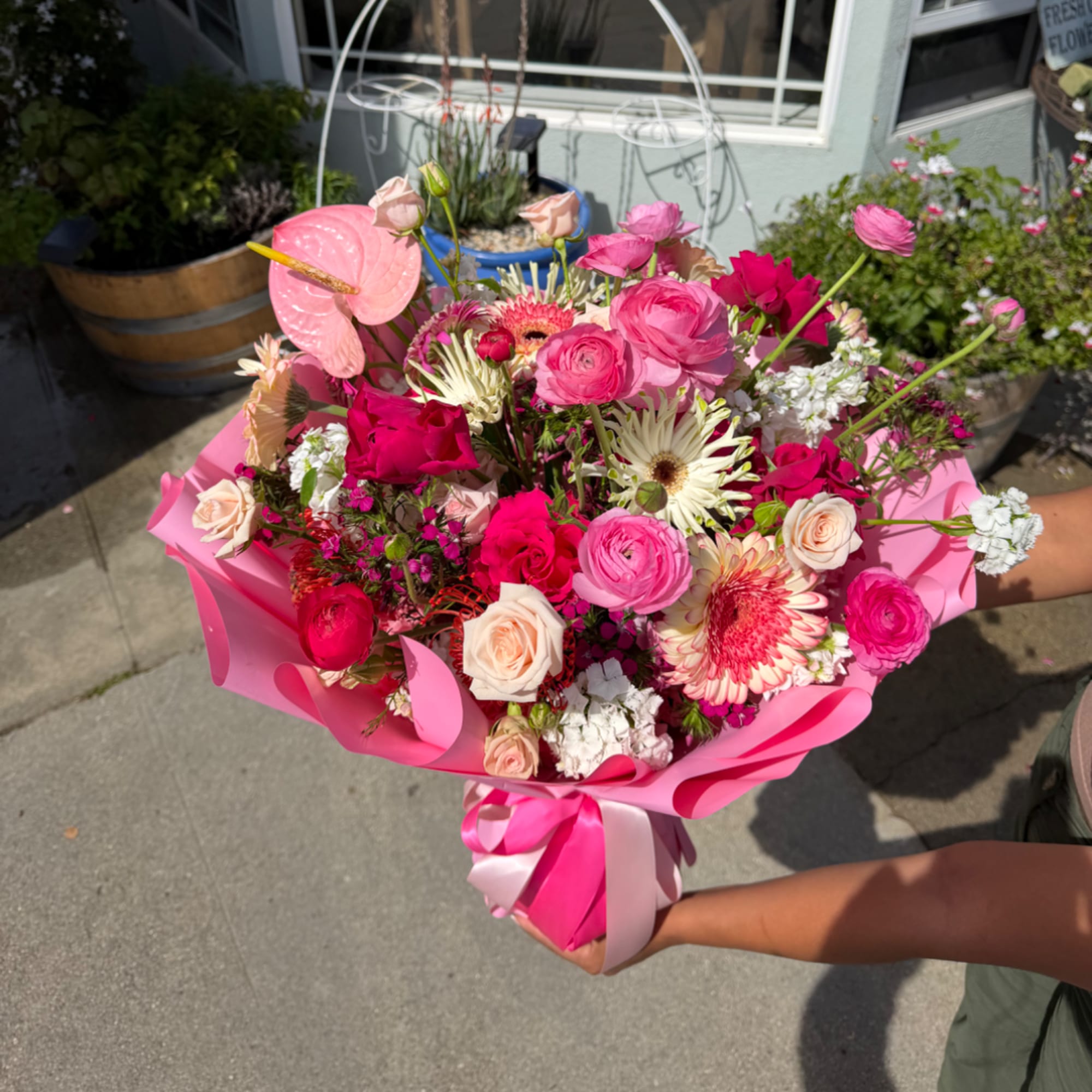 Pink mixed bouquet with roses, ranunculus, and gerbera daisies wrapped in bright pink paper