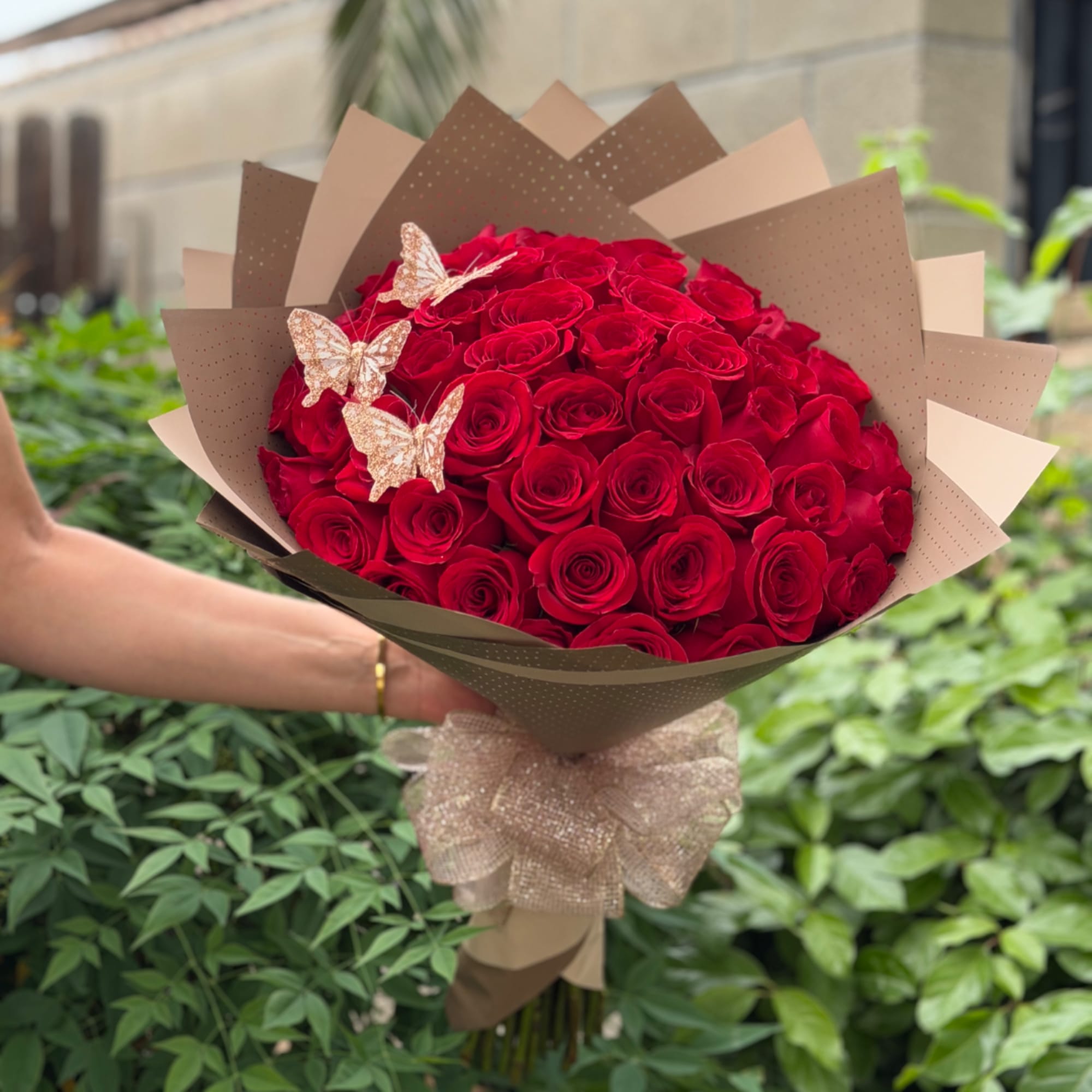 Bouquet of red roses wrapped in brown paper with butterfly decorations