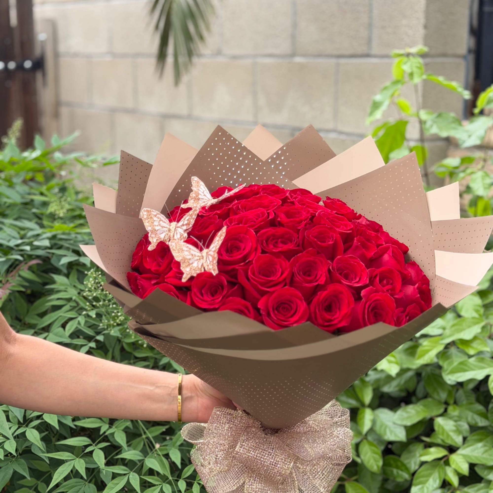 Bouquet of red roses wrapped in brown paper with butterfly accents