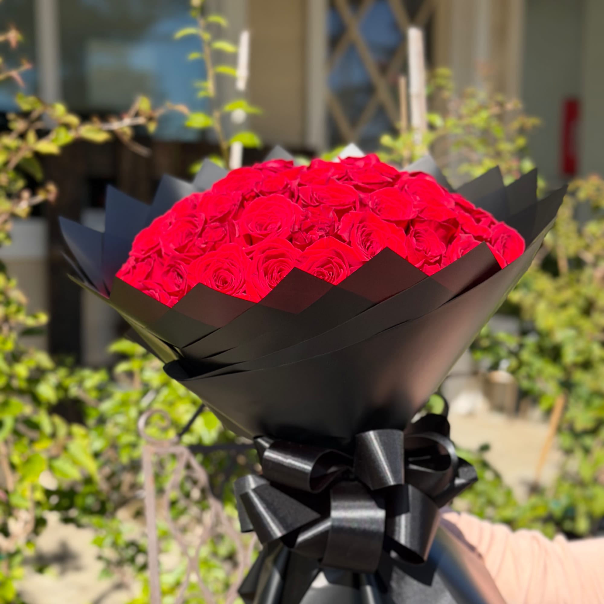 Bouquet of red roses wrapped in black paper with a black ribbon