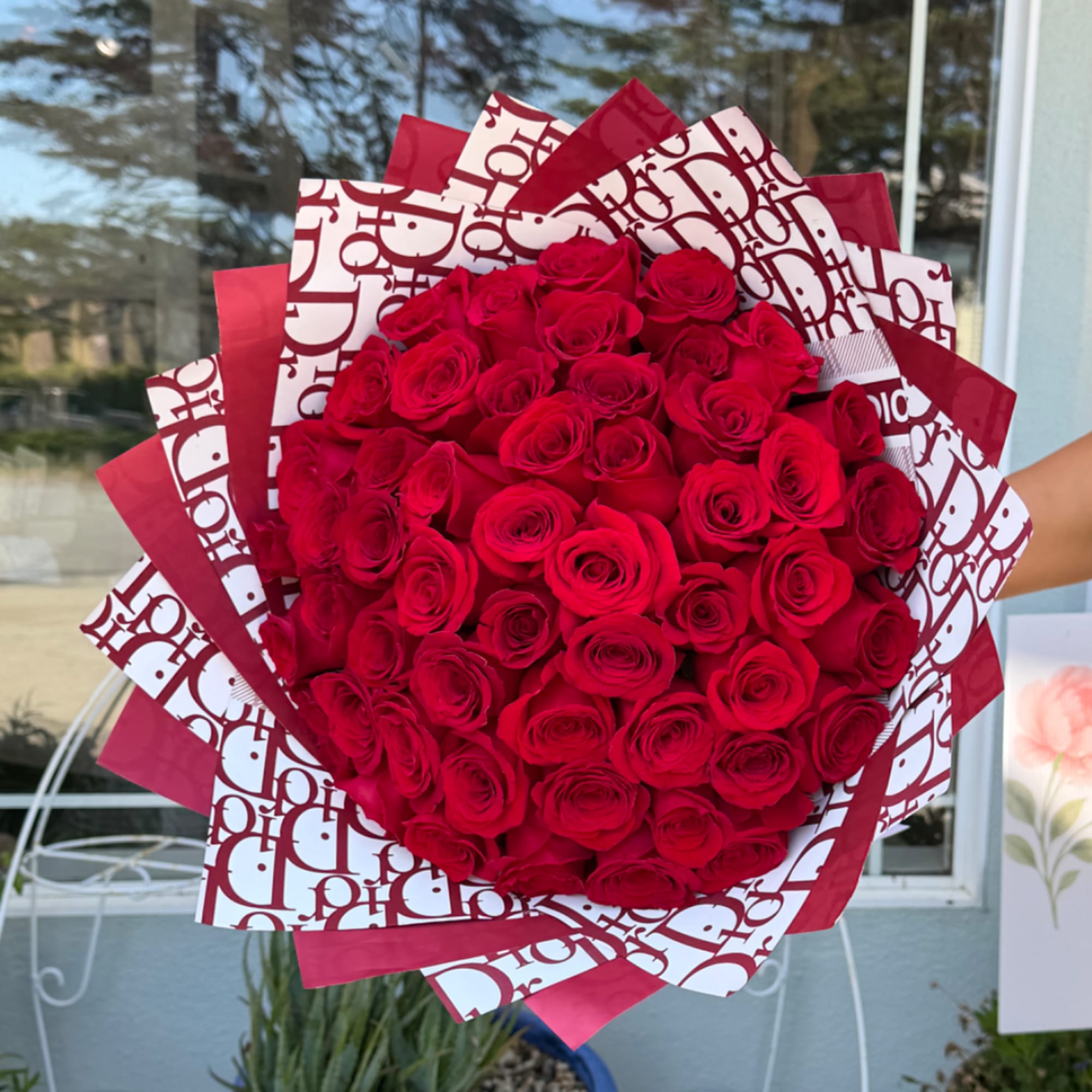 Large bouquet of red roses wrapped in patterned red and white paper