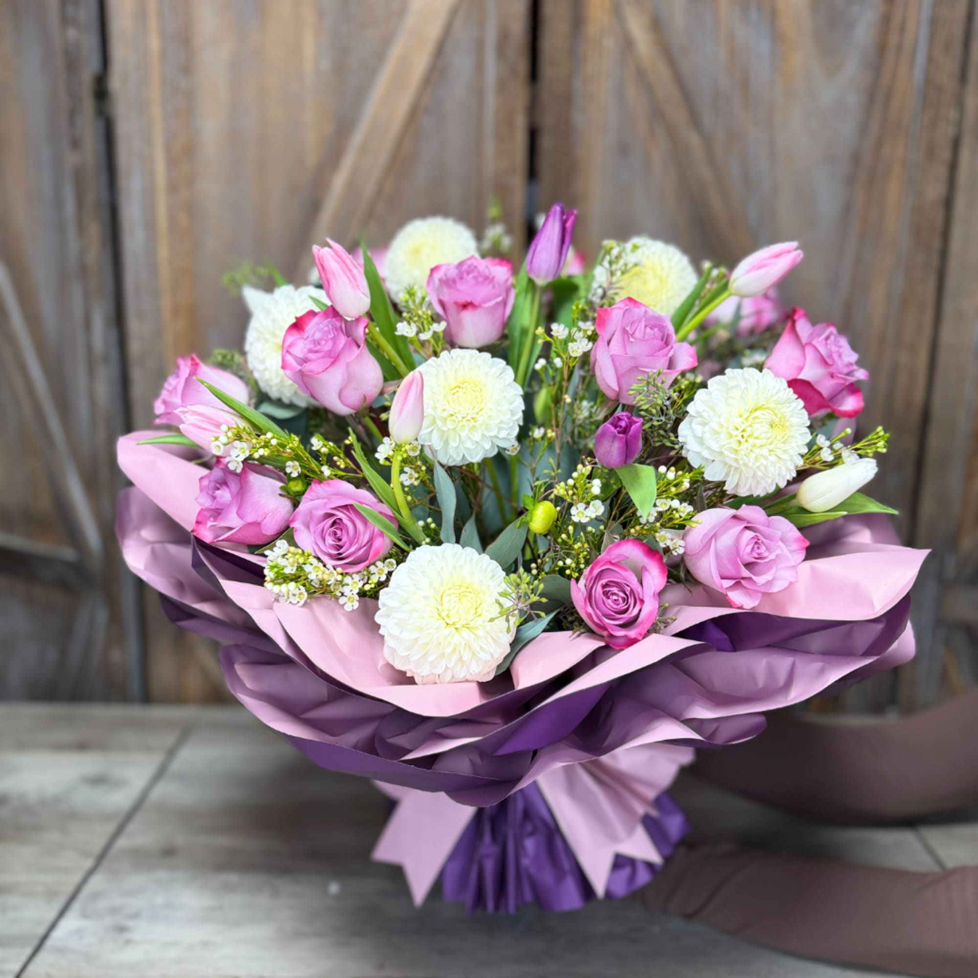 Pink roses and white pom flowers in purple wrapping