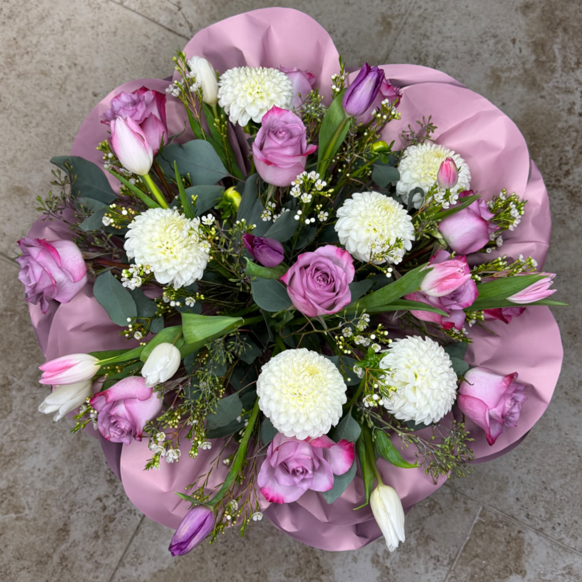 Pink and white bouquet with roses, tulips, and round white blooms wrapped in pink paper