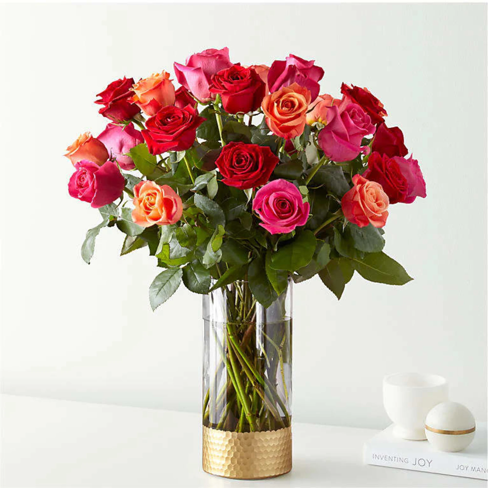 Bouquet of red, pink, and orange roses in a tall glass vase