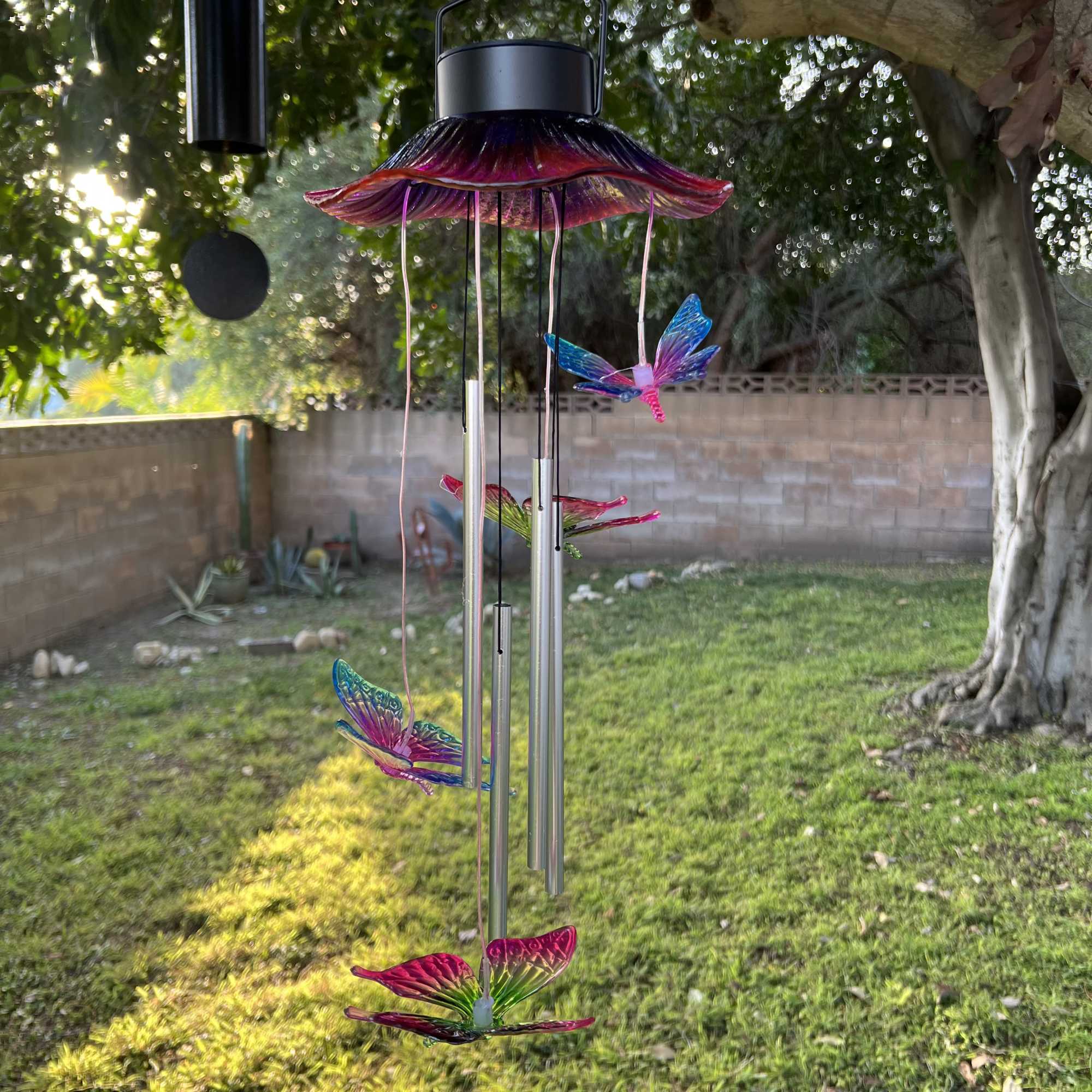 Colorful butterfly wind chime hanging outdoors in a yard