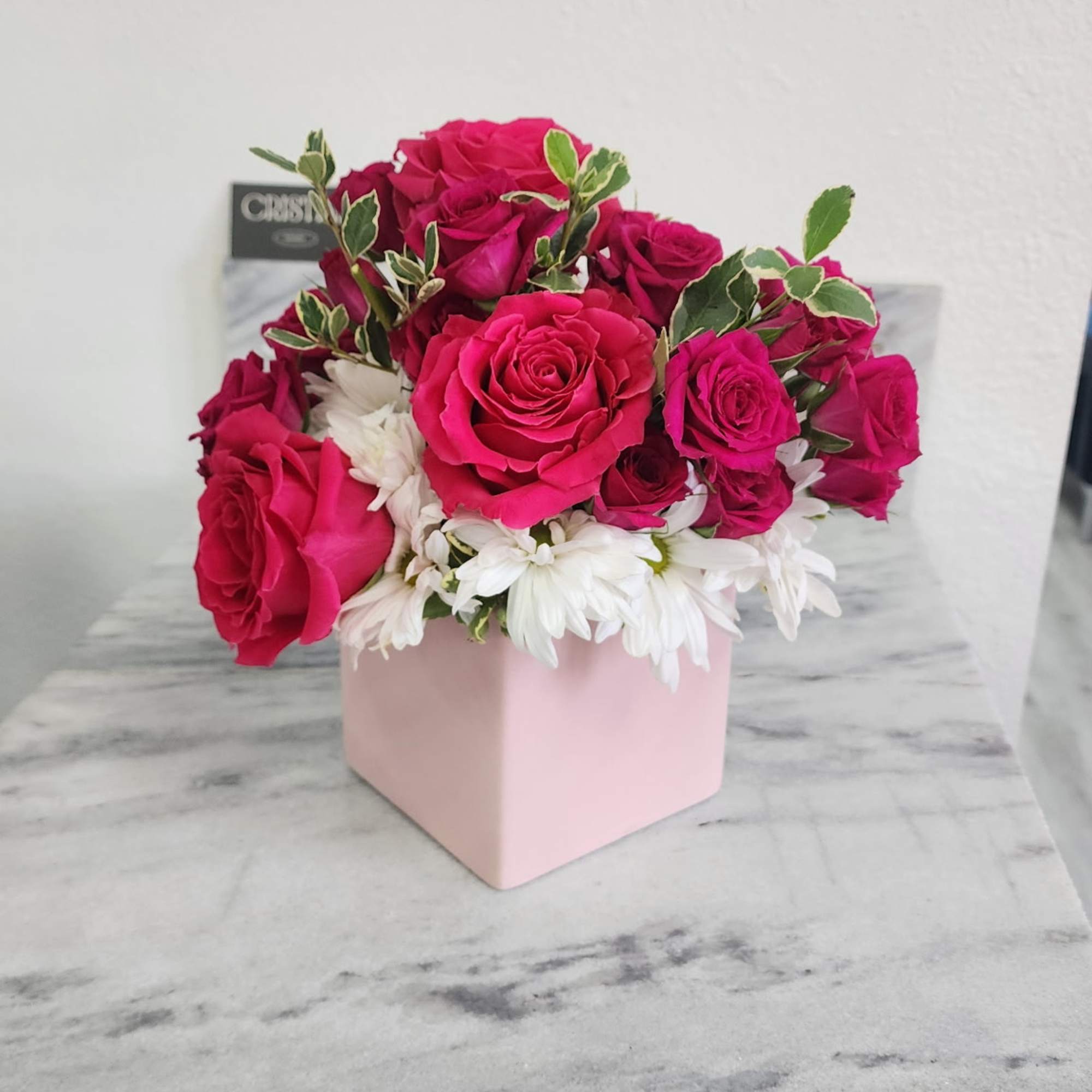 Pink roses and white daisies arranged in a pale pink box