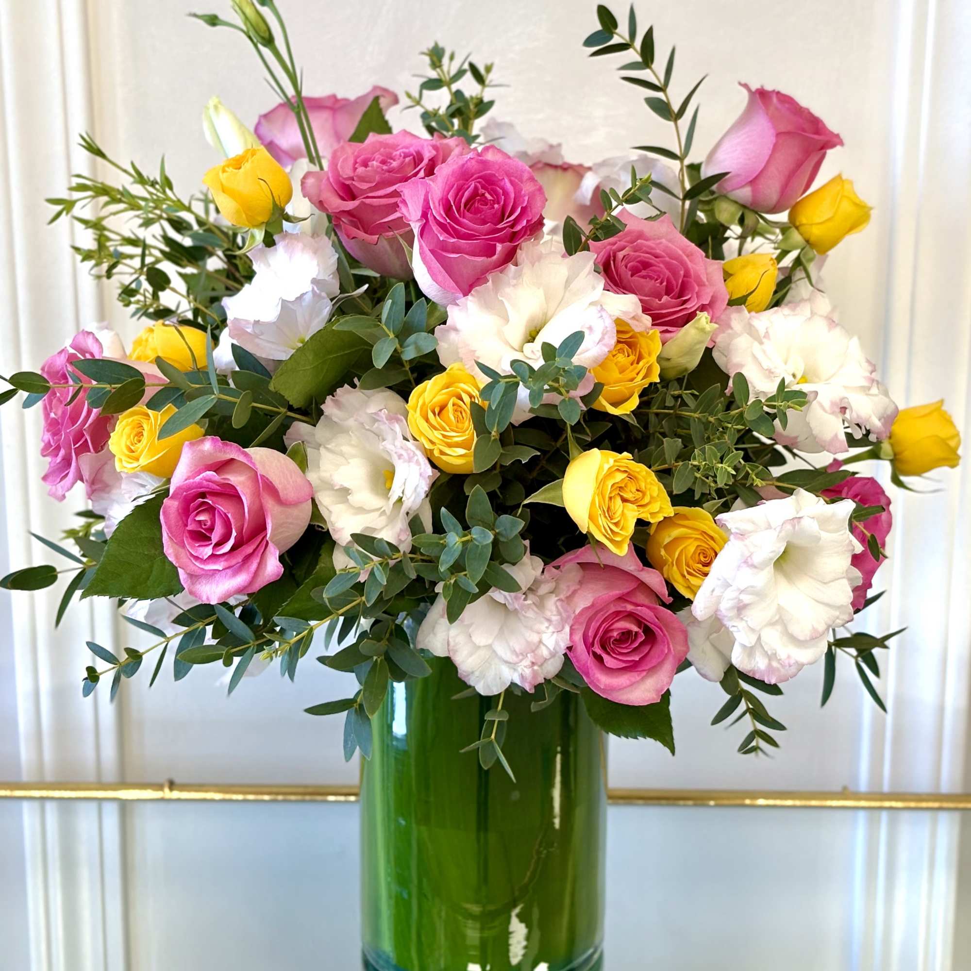 A vibrant bouquet of pink roses, golden yellow spray roses, white lisianthus