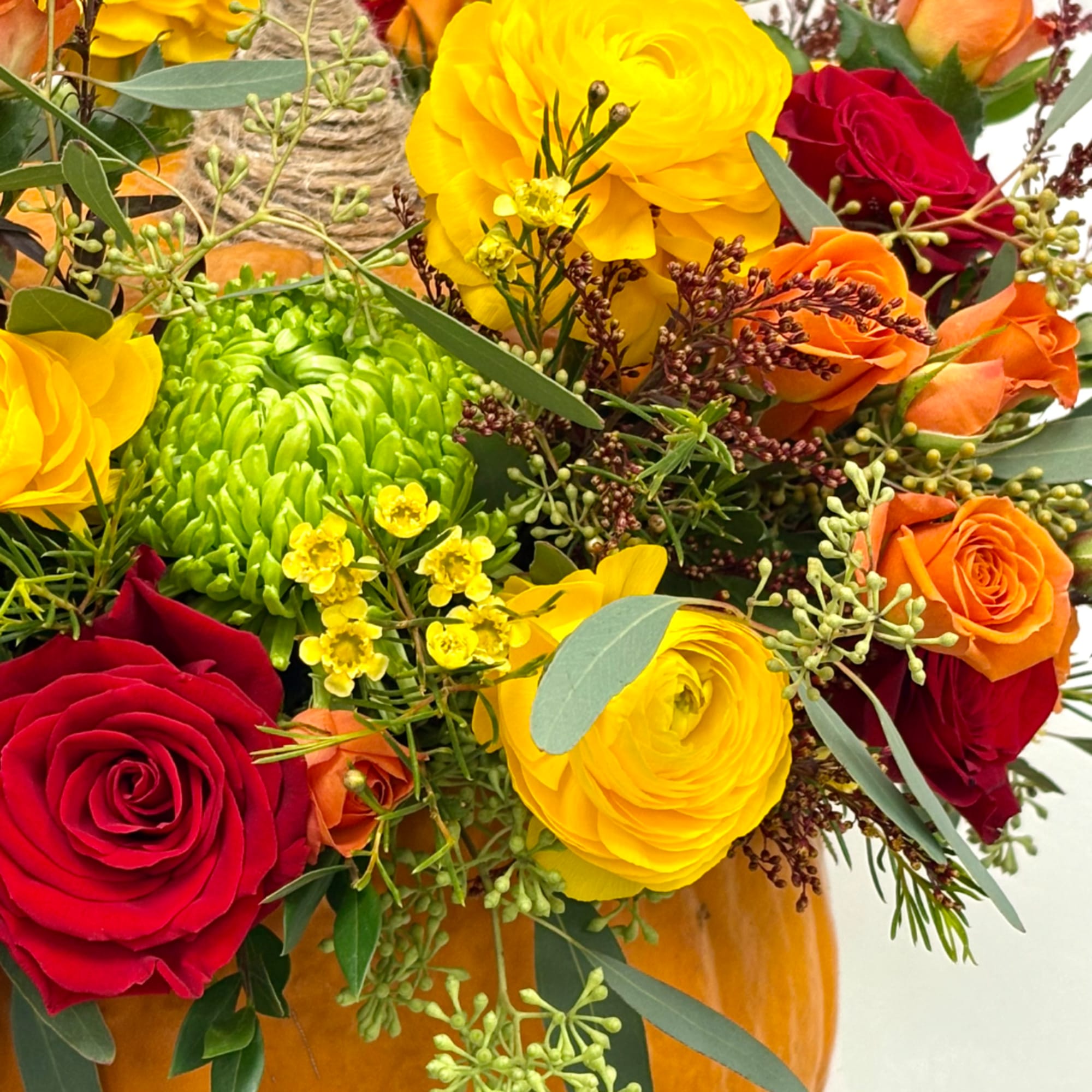 Bouquet of red, orange, and yellow flowers in a pumpkin vase