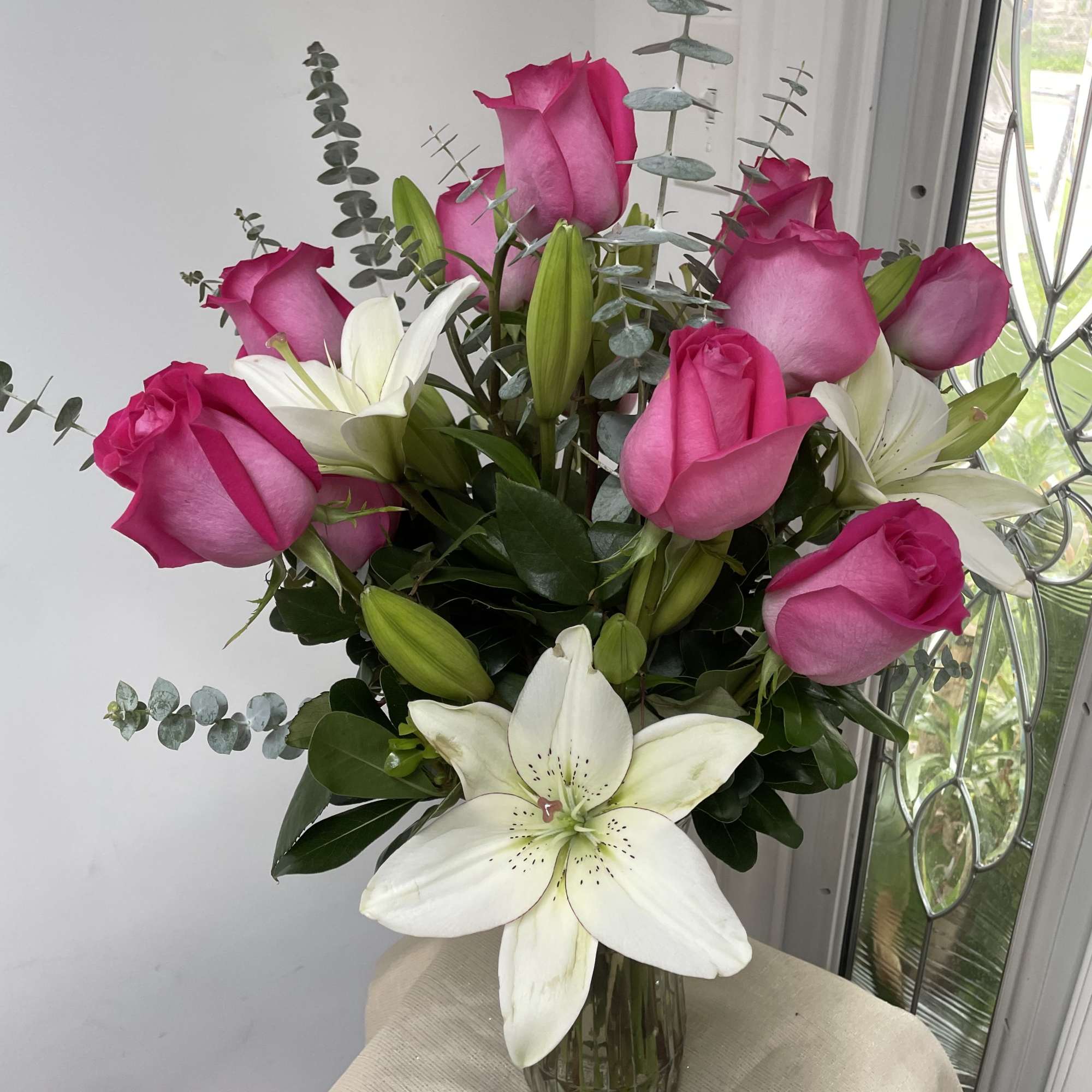 Pink roses and white lilies arranged in a glass vase
