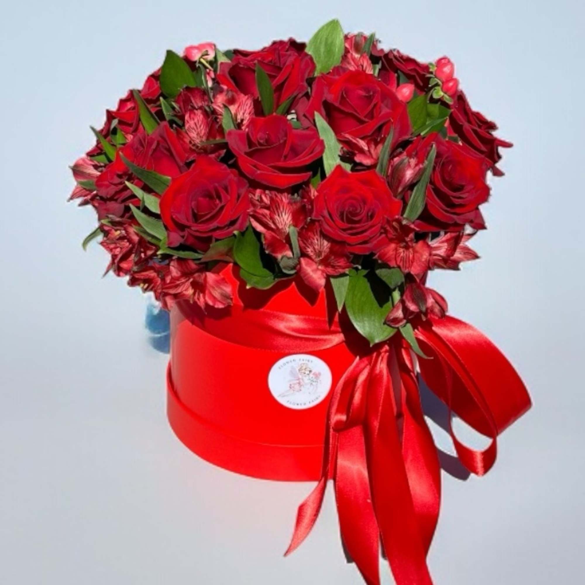 Red roses and pink alstroemeria in a red hat box with a satin ribbon