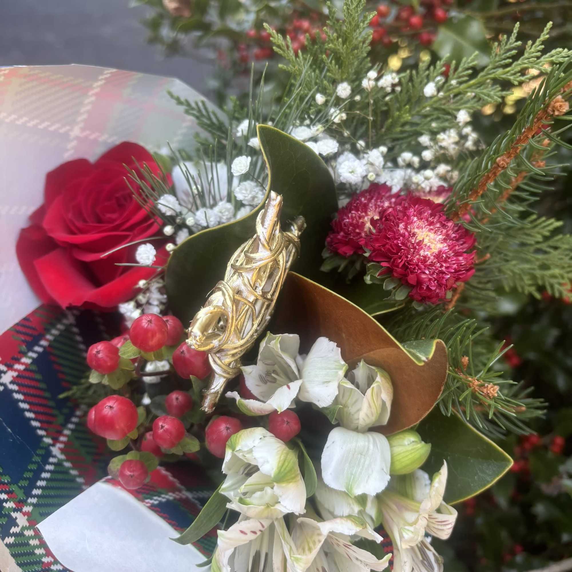 Bouquet with red roses, white alstroemeria, and red berries in festive wrap
