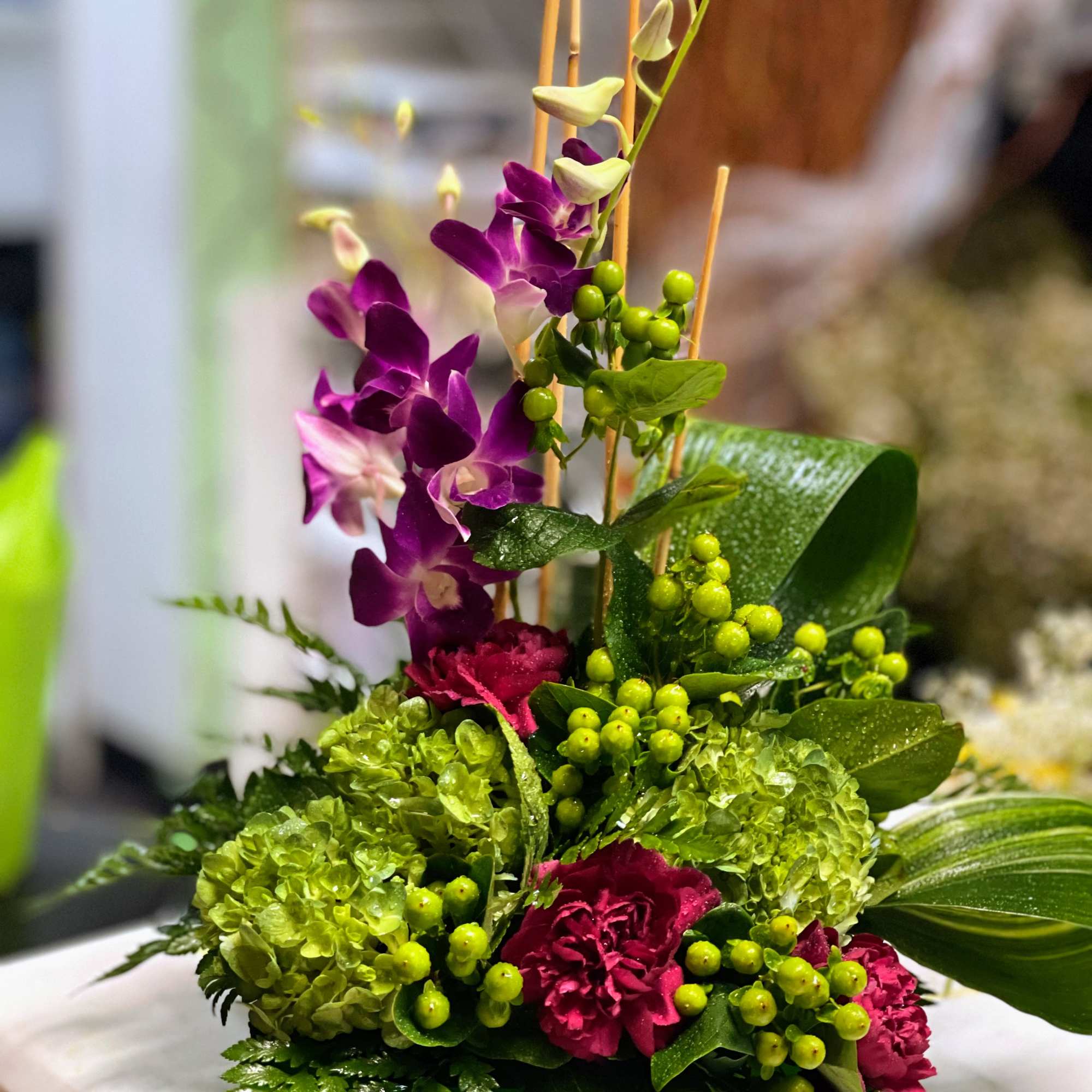 Purple orchids and green blooms in a low rectangular container