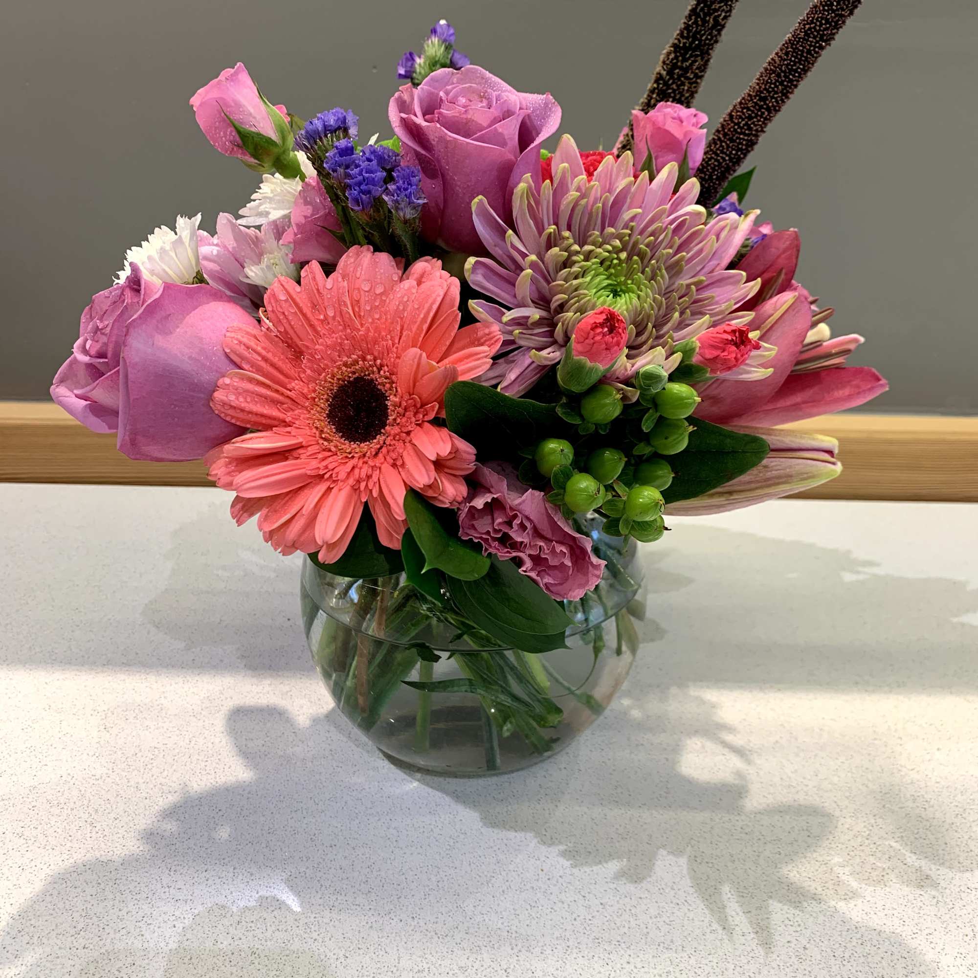 Mixed pink and purple bouquet in a round glass vase