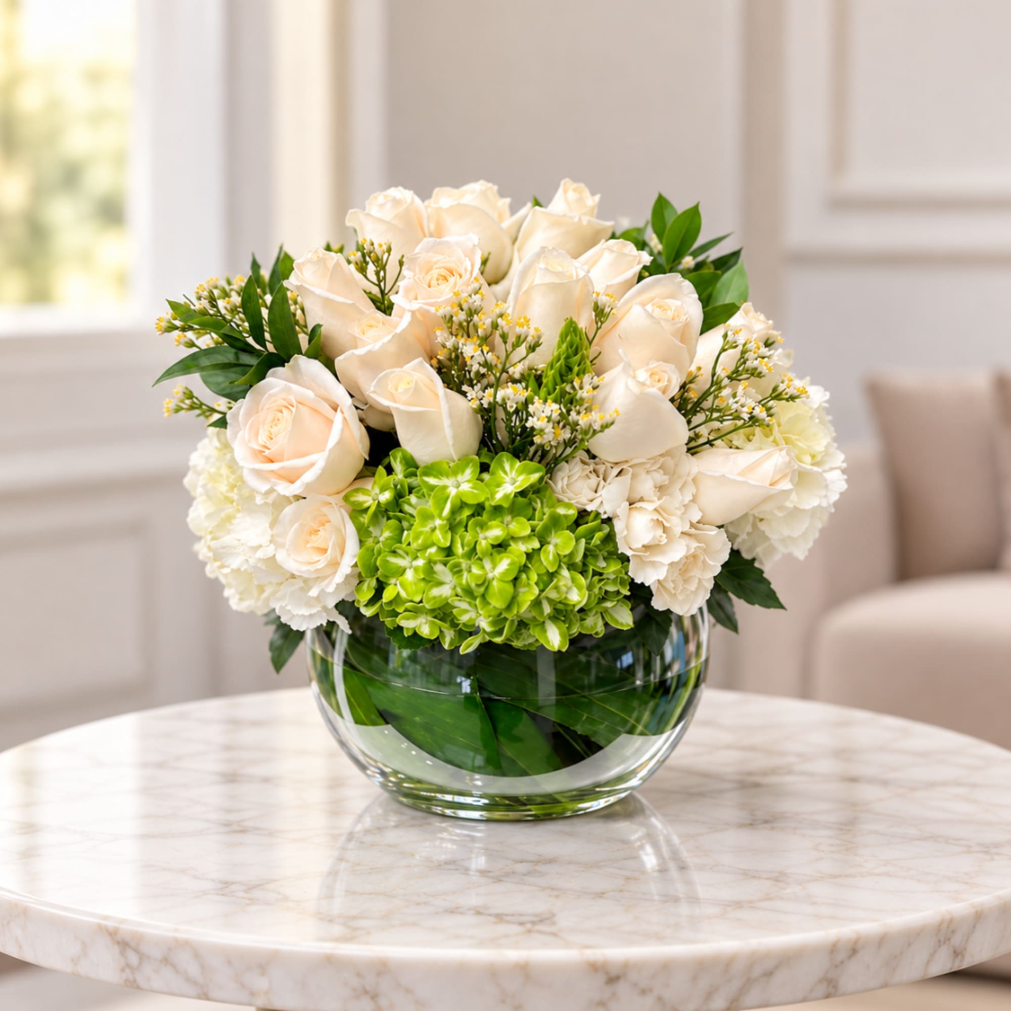 Cream roses and white flowers arranged in a clear glass bowl vase