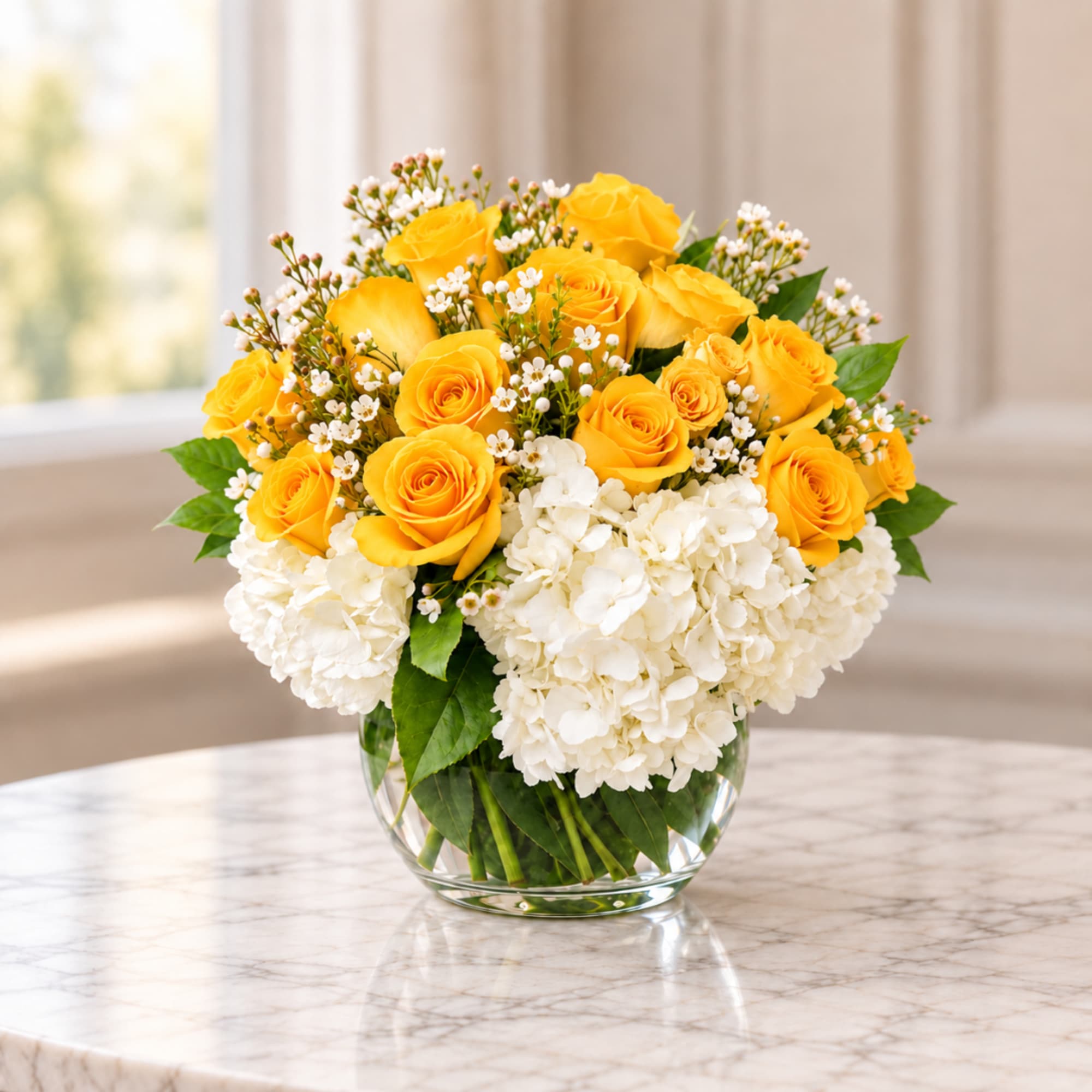 Yellow roses and white hydrangeas in a clear glass vase
