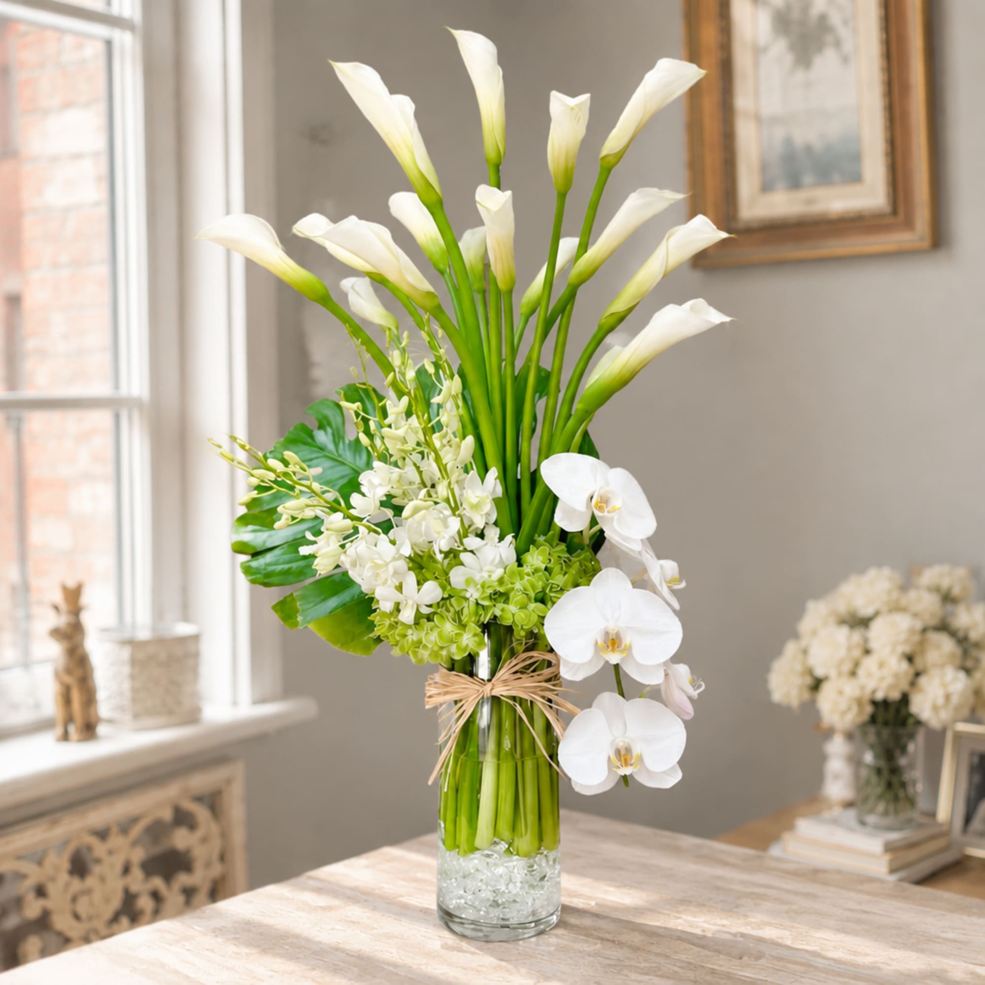 White calla lilies and orchids arranged in a glass vase