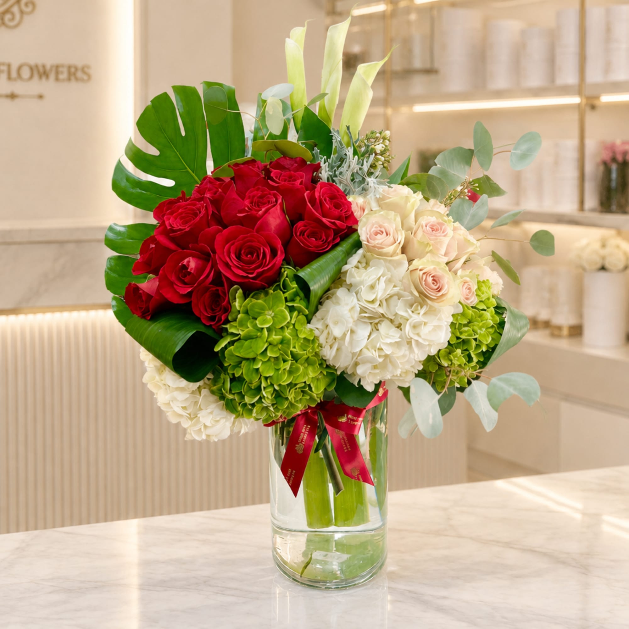 Red and blush roses with white hydrangeas in a clear glass vase