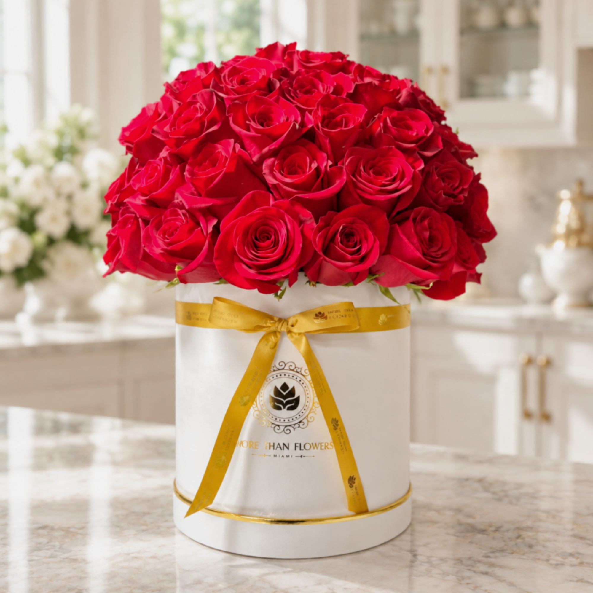 Red roses arranged in a white round box with a gold ribbon