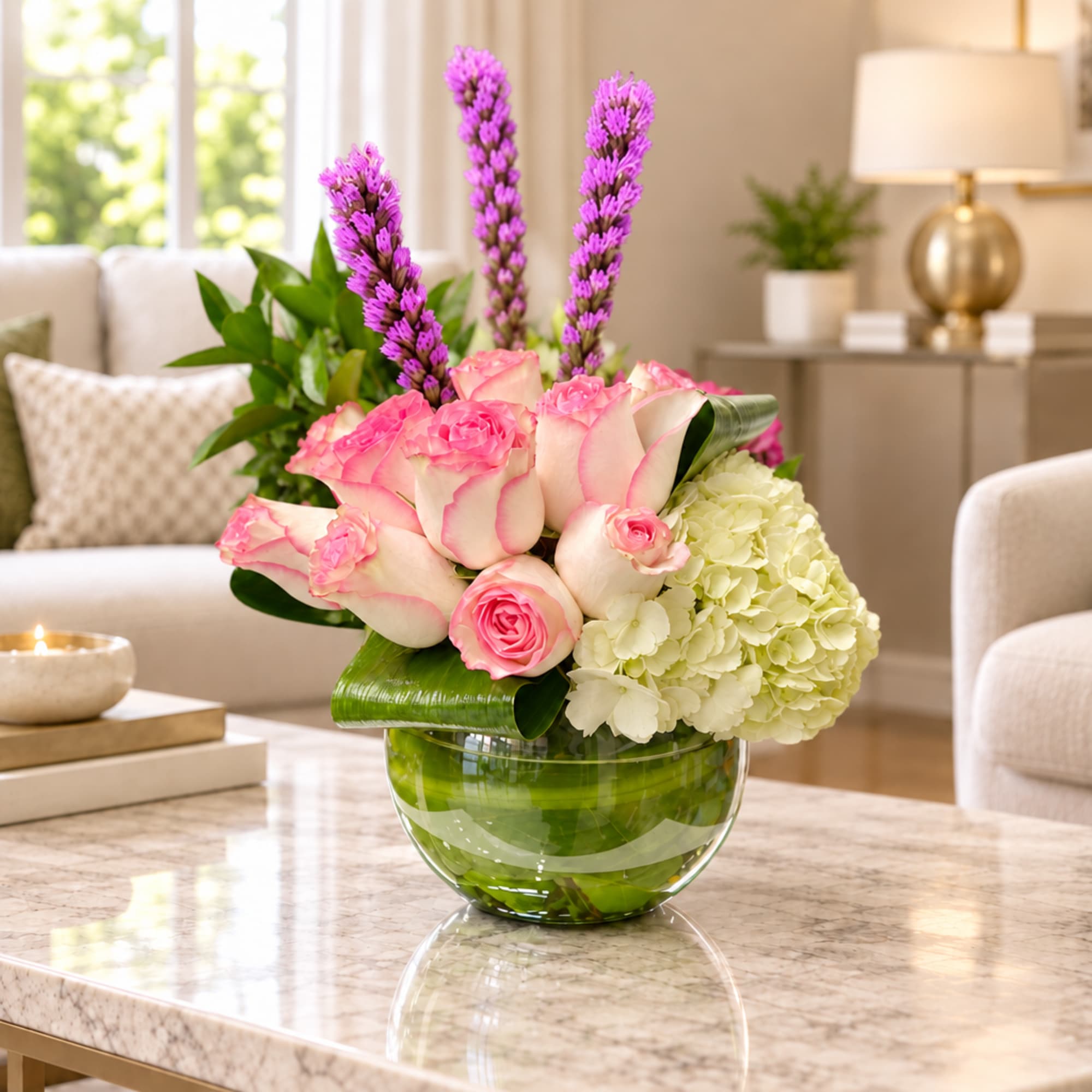Pink roses and white hydrangea in a glass bowl vase with purple spikes