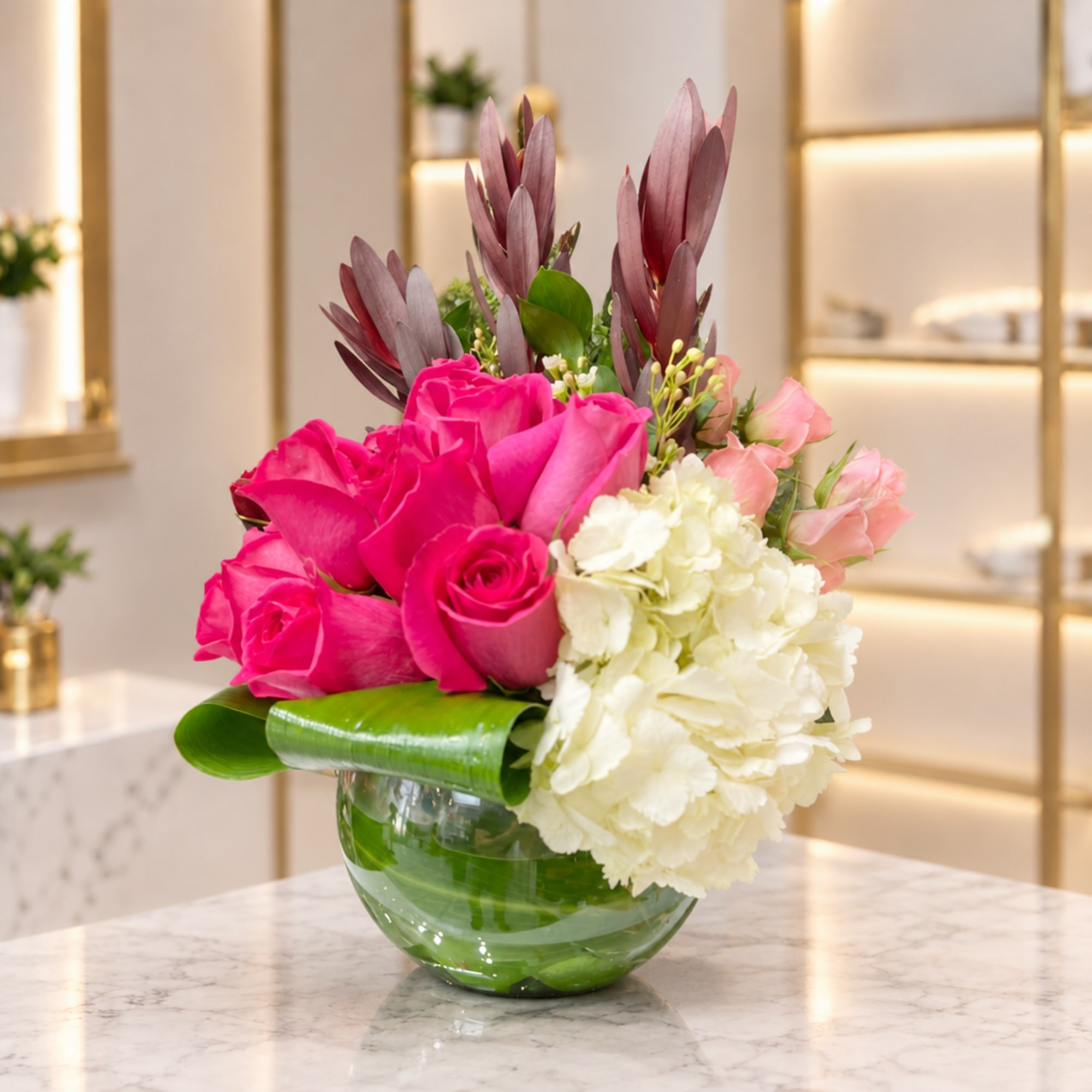 Pink roses and white hydrangeas in a glass vase with tall burgundy foliage