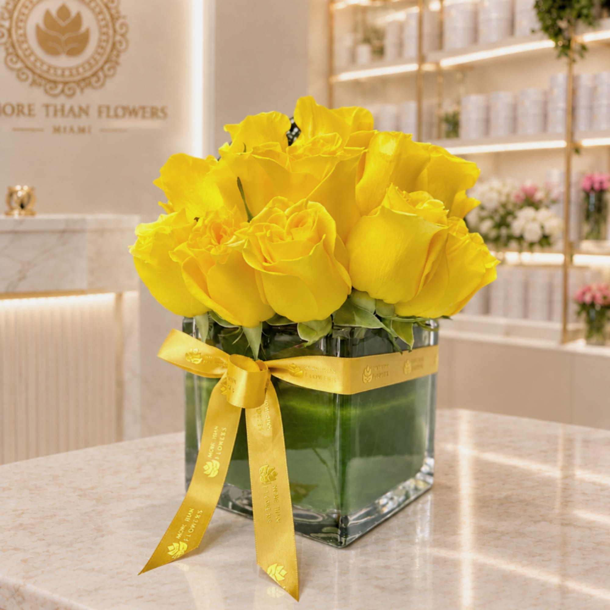 Yellow roses in a square glass vase with a yellow ribbon