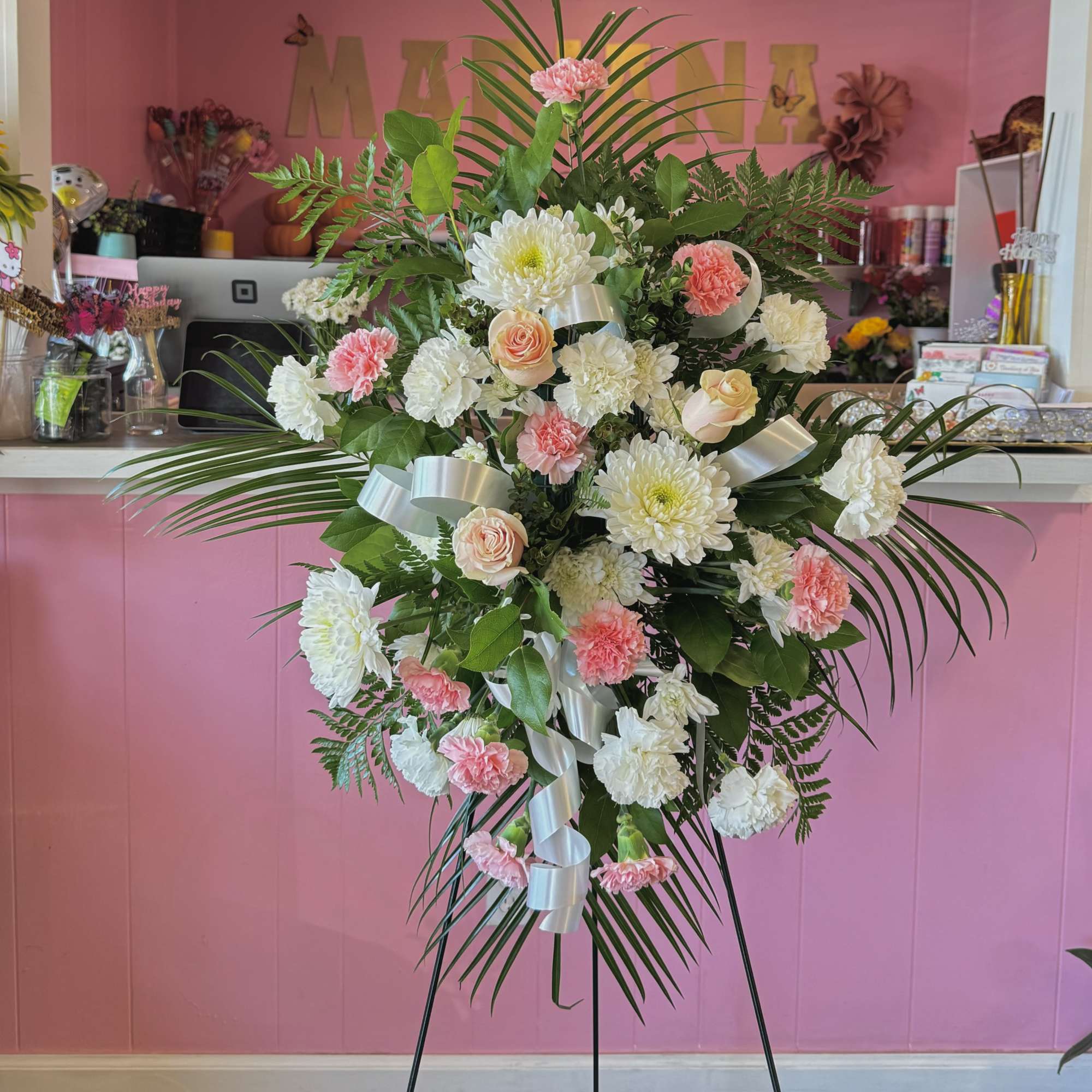 Standing floral spray with pink and white flowers on a metal easel