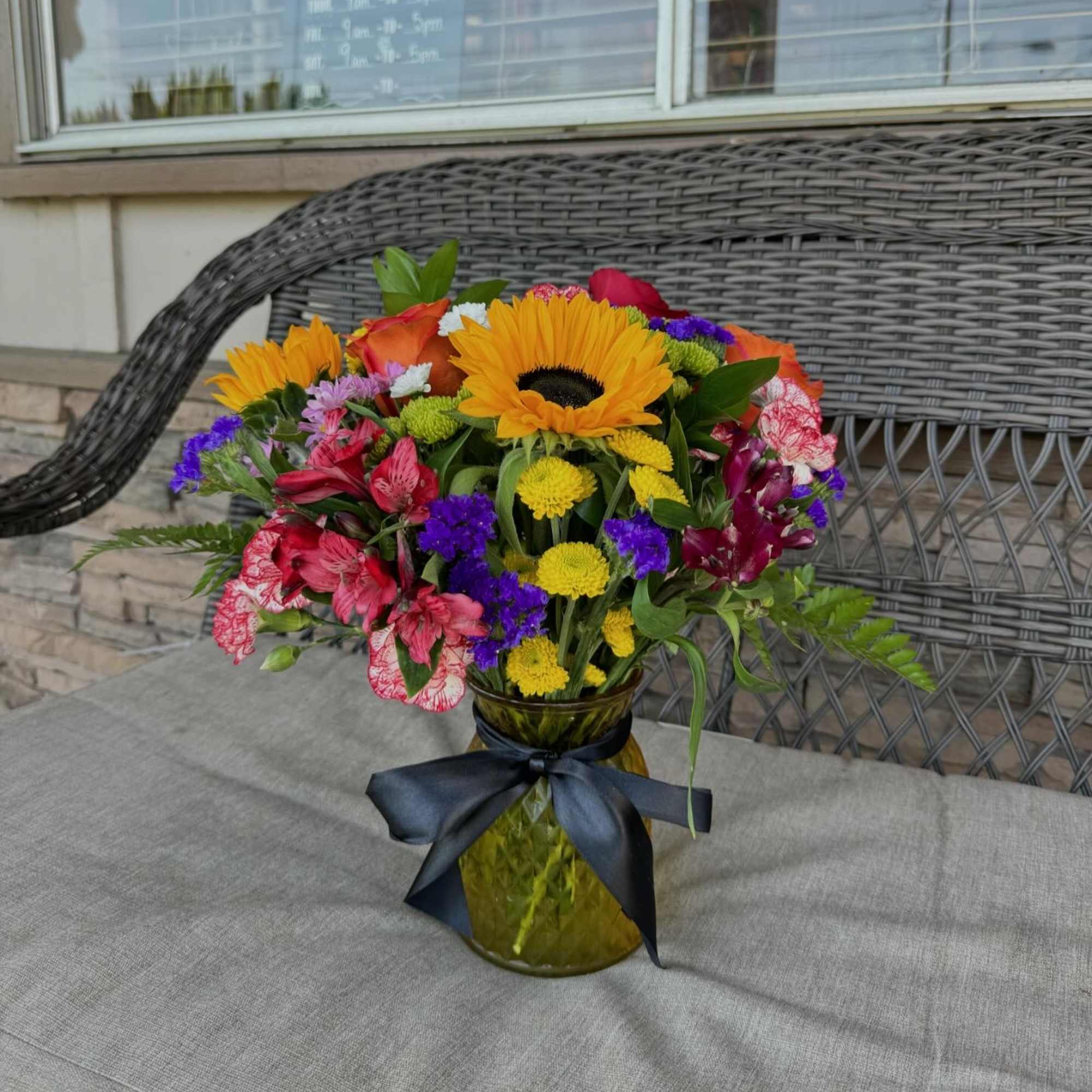 Colorful mixed bouquet in a glass vase with a dark ribbon