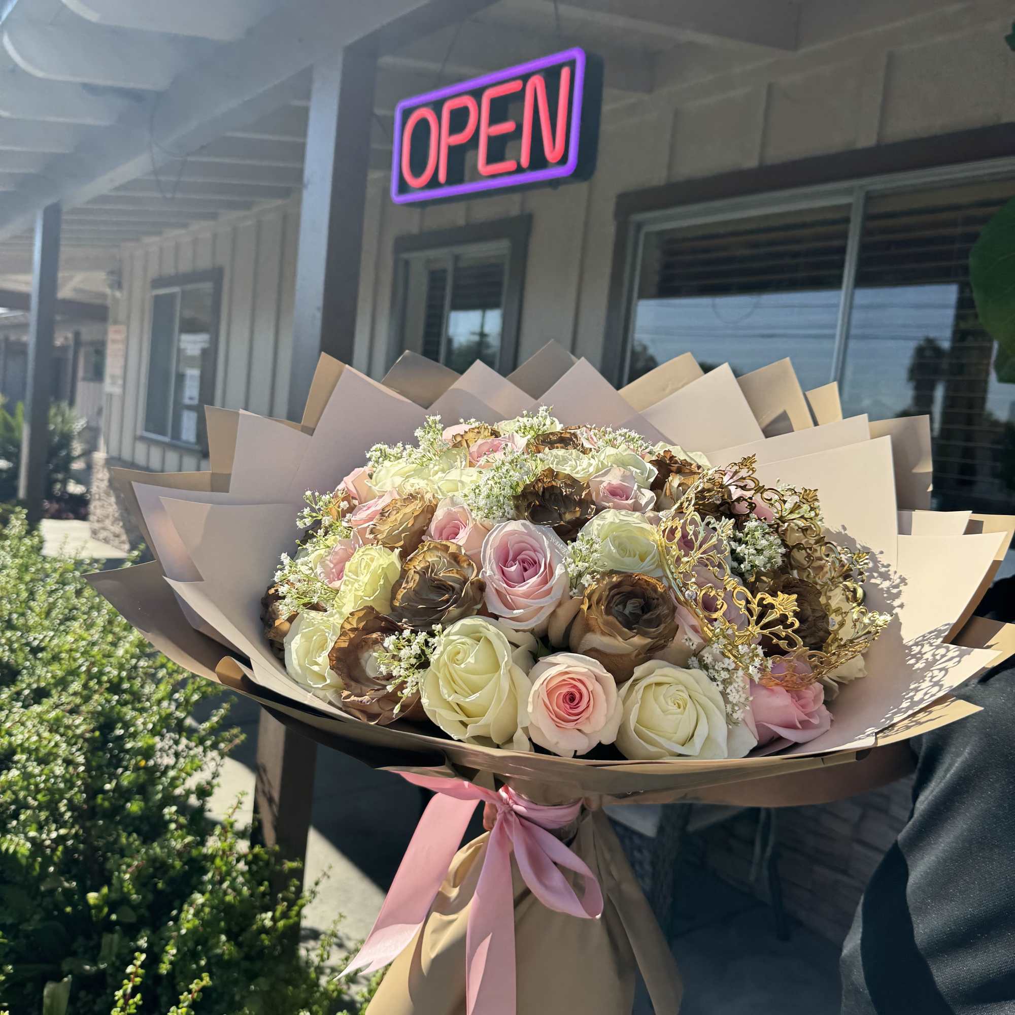 Large bouquet of pink and cream roses wrapped in tan paper with a pink ribbon
