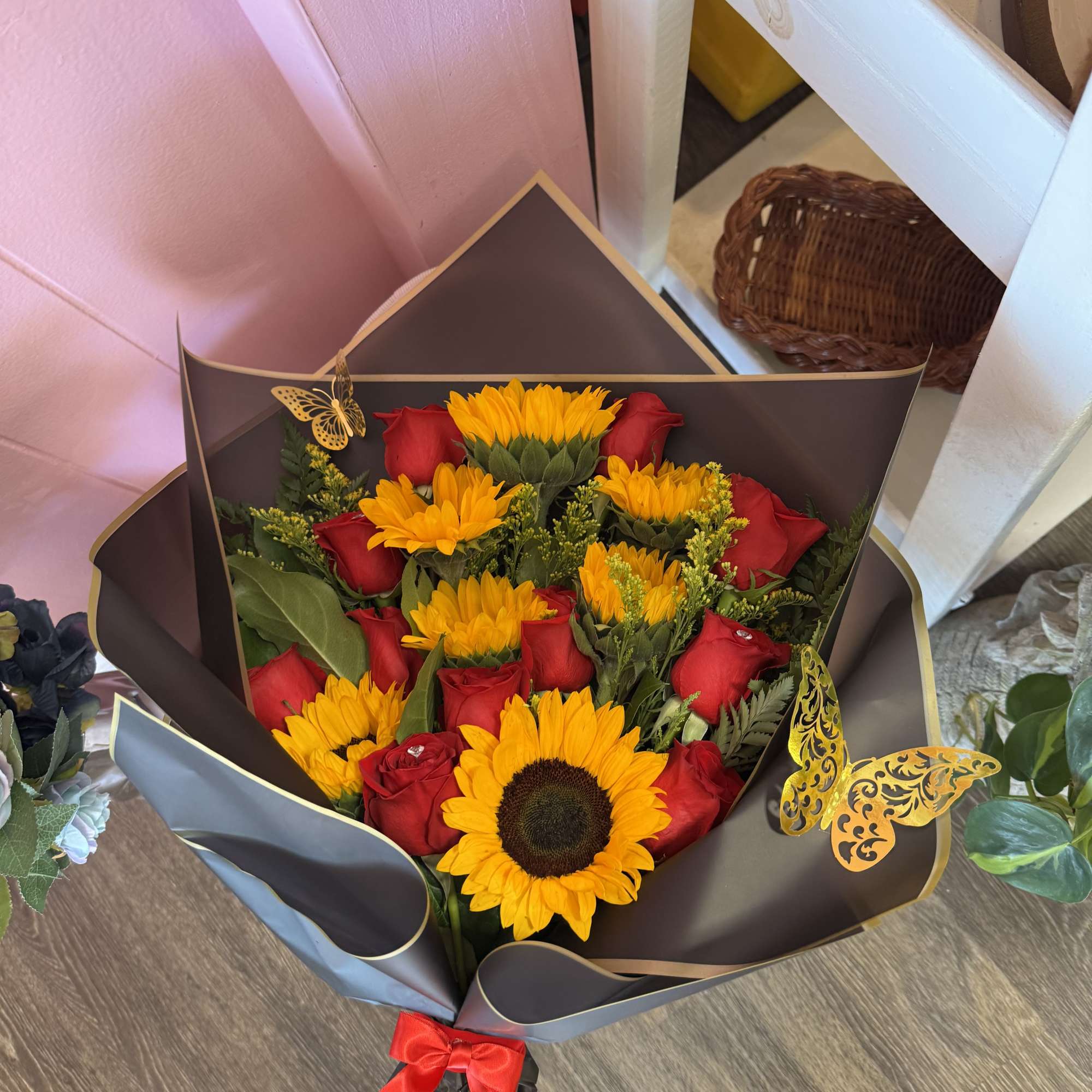 Bouquet of red roses and yellow sunflowers wrapped in dark paper