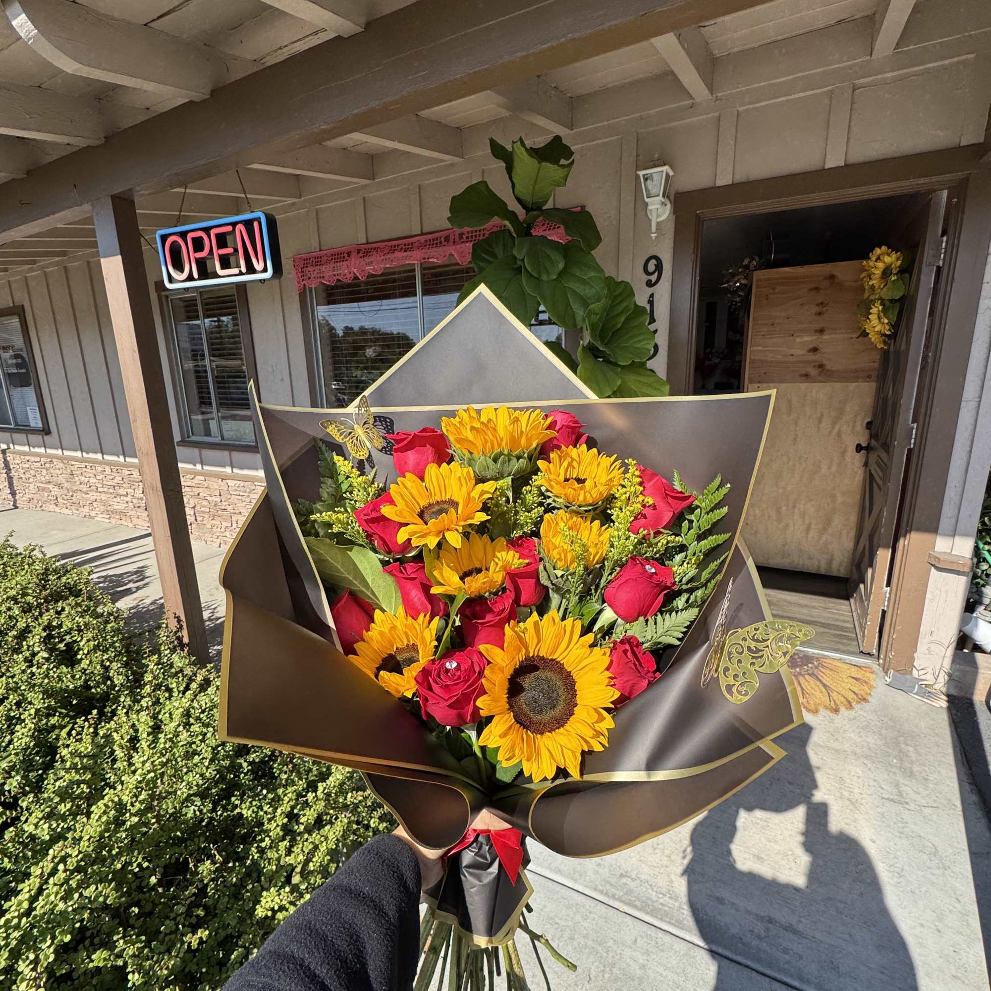 Bouquet of sunflowers and red roses wrapped in dark paper