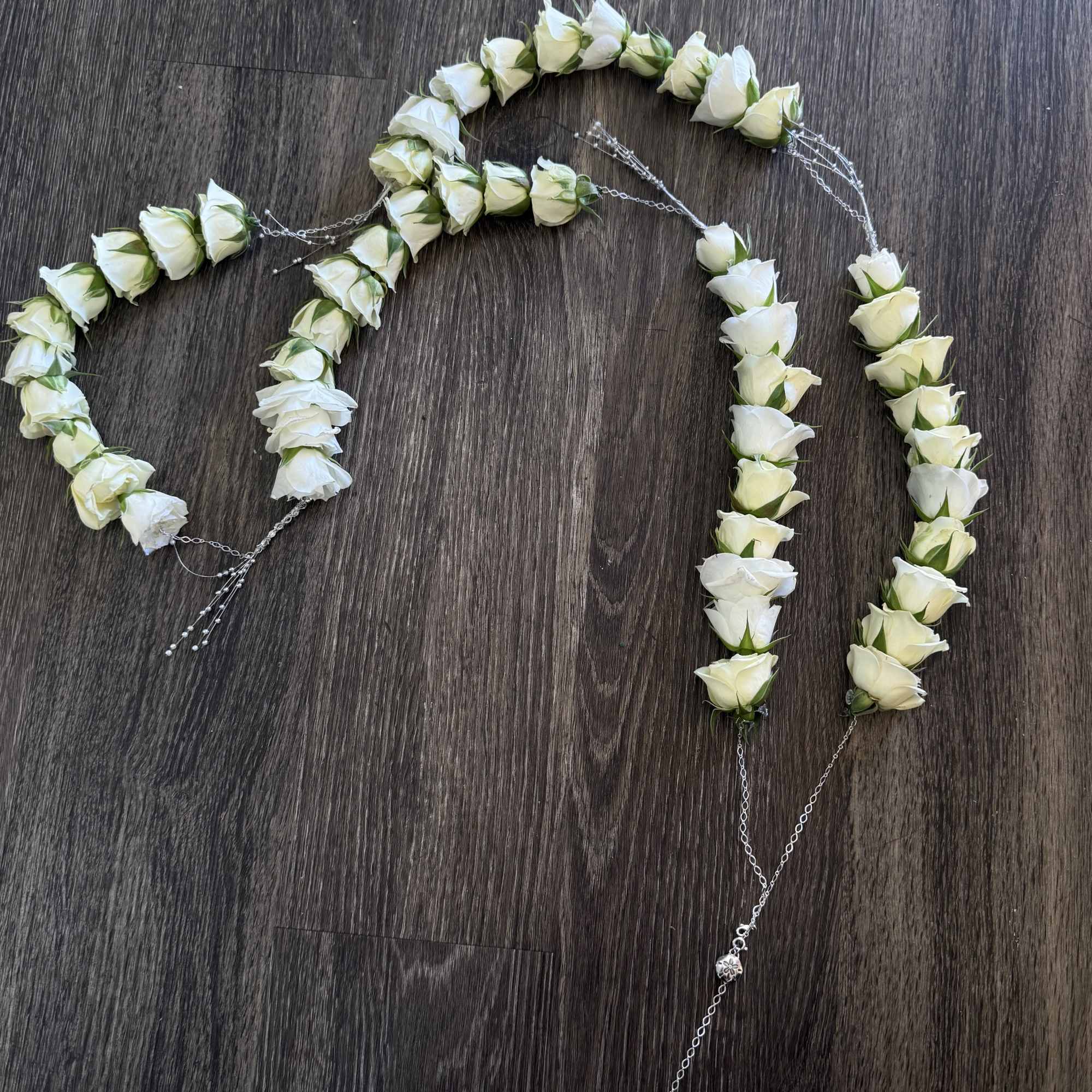 White rose garlands arranged on a dark wood floor