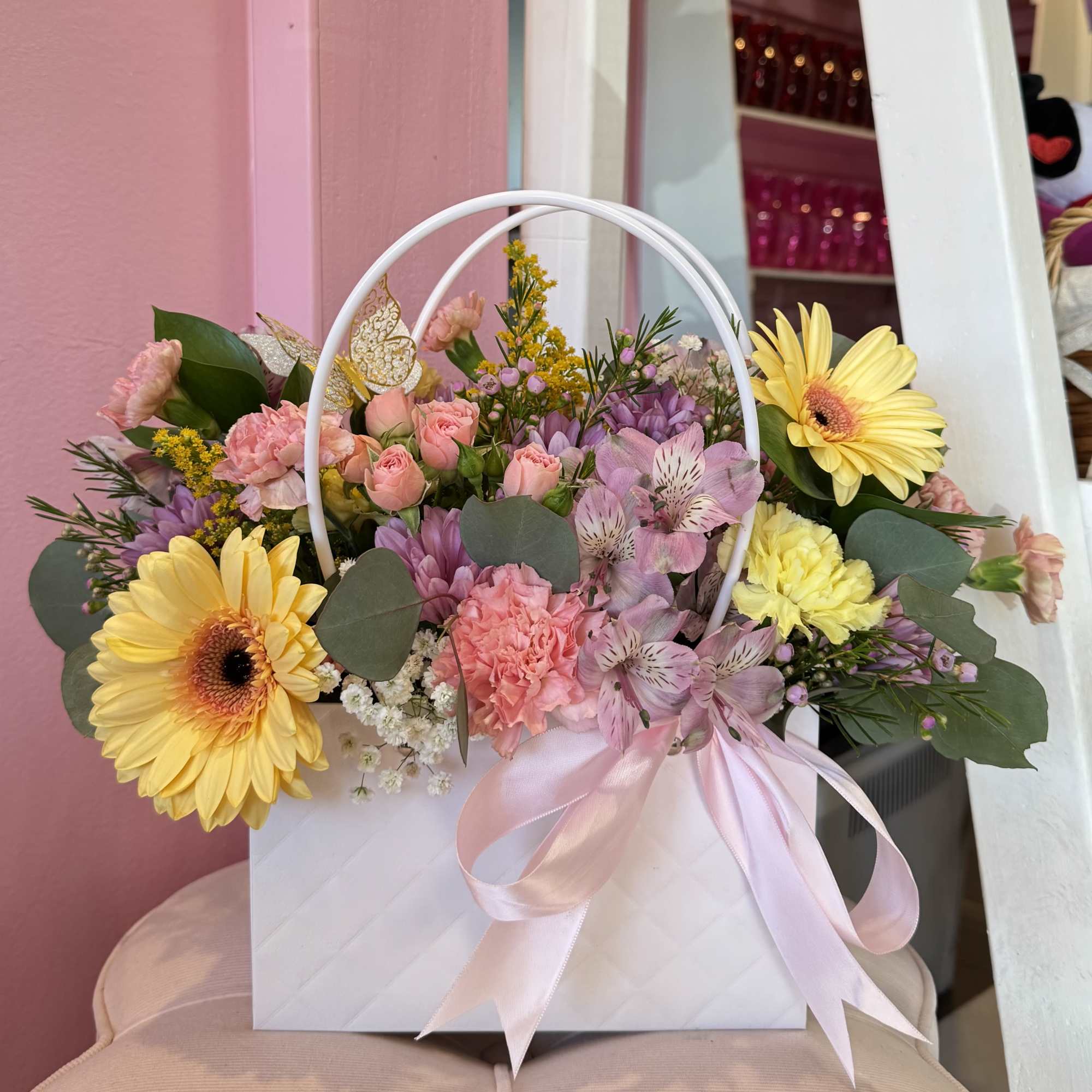 Pastel flower arrangement in a white gift bag with pink ribbon