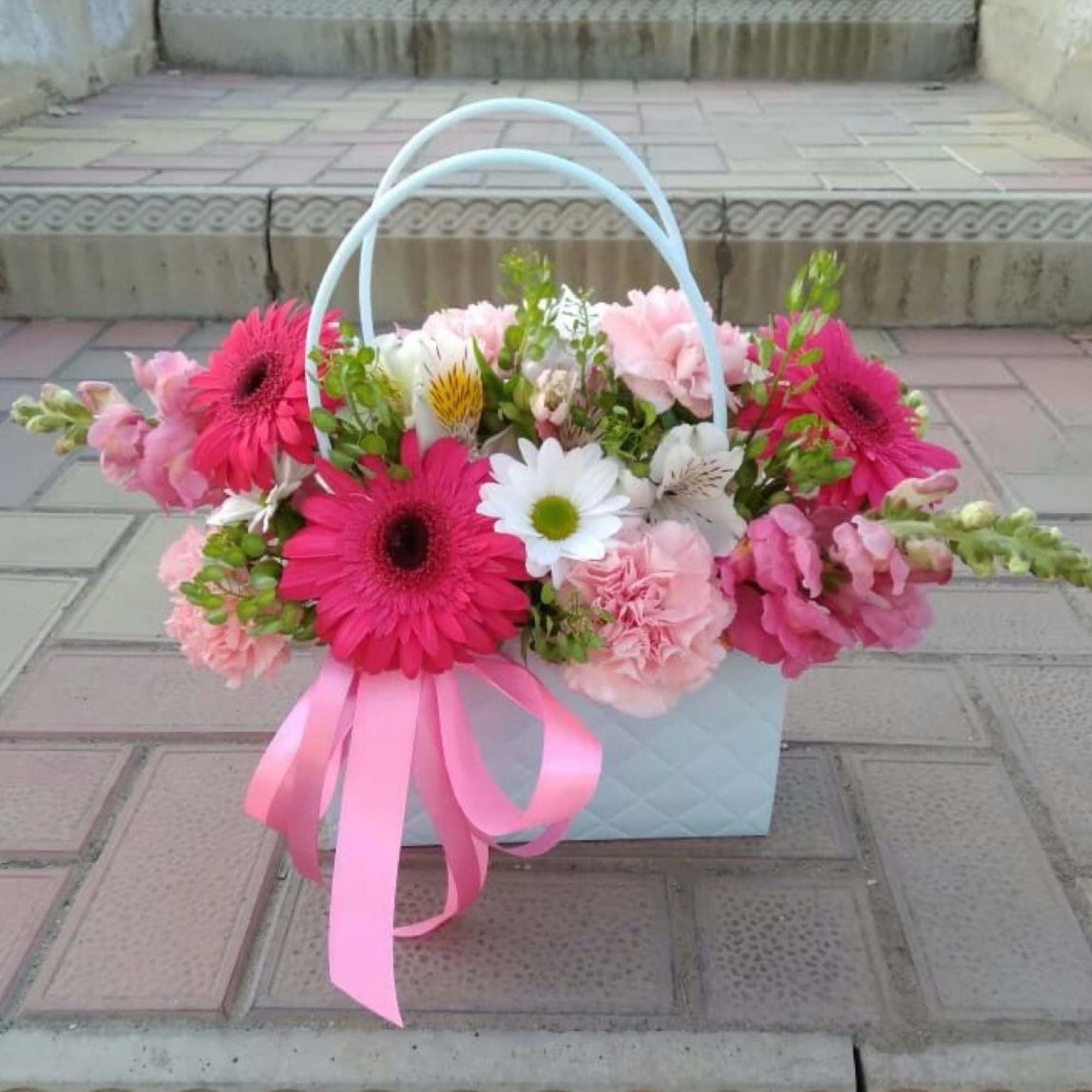 Pink and white flower basket with a ribbon bow
