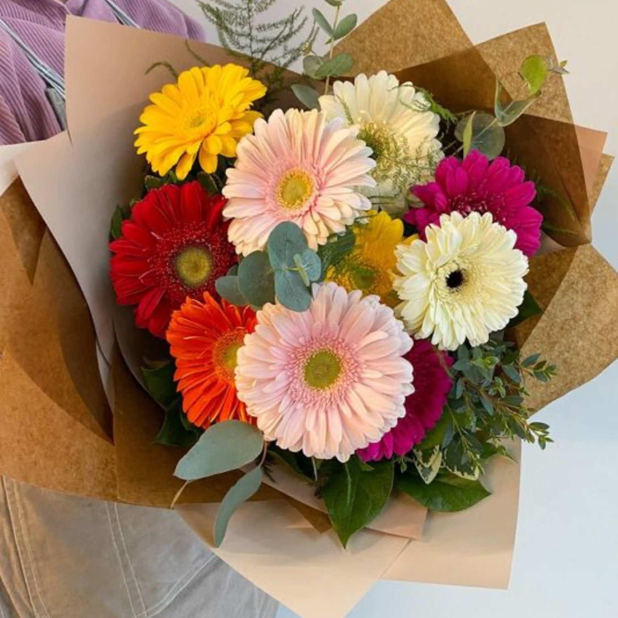Bouquet of multicolored gerbera daisies wrapped in brown paper