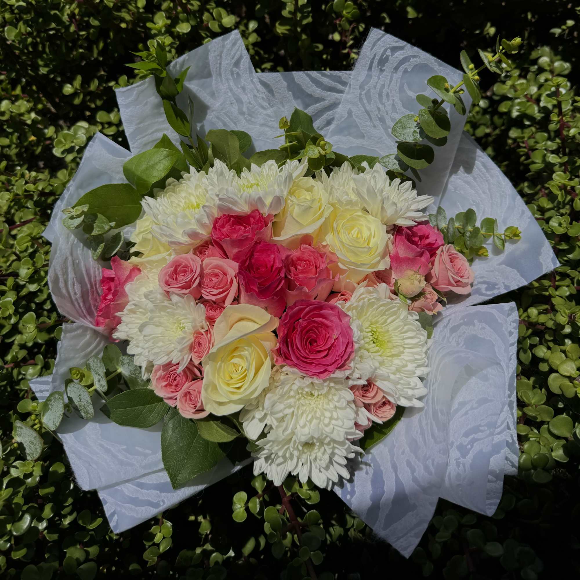 Bouquet of pink and white roses with white chrysanthemums wrapped in white paper