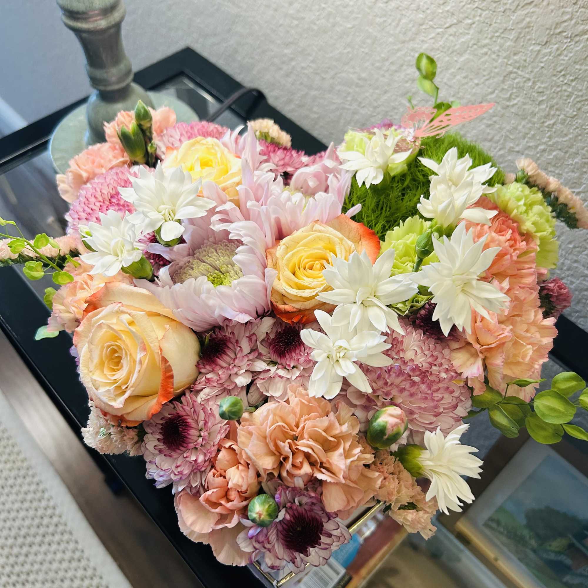 Mixed bouquet of pink, peach, and white flowers in a low container