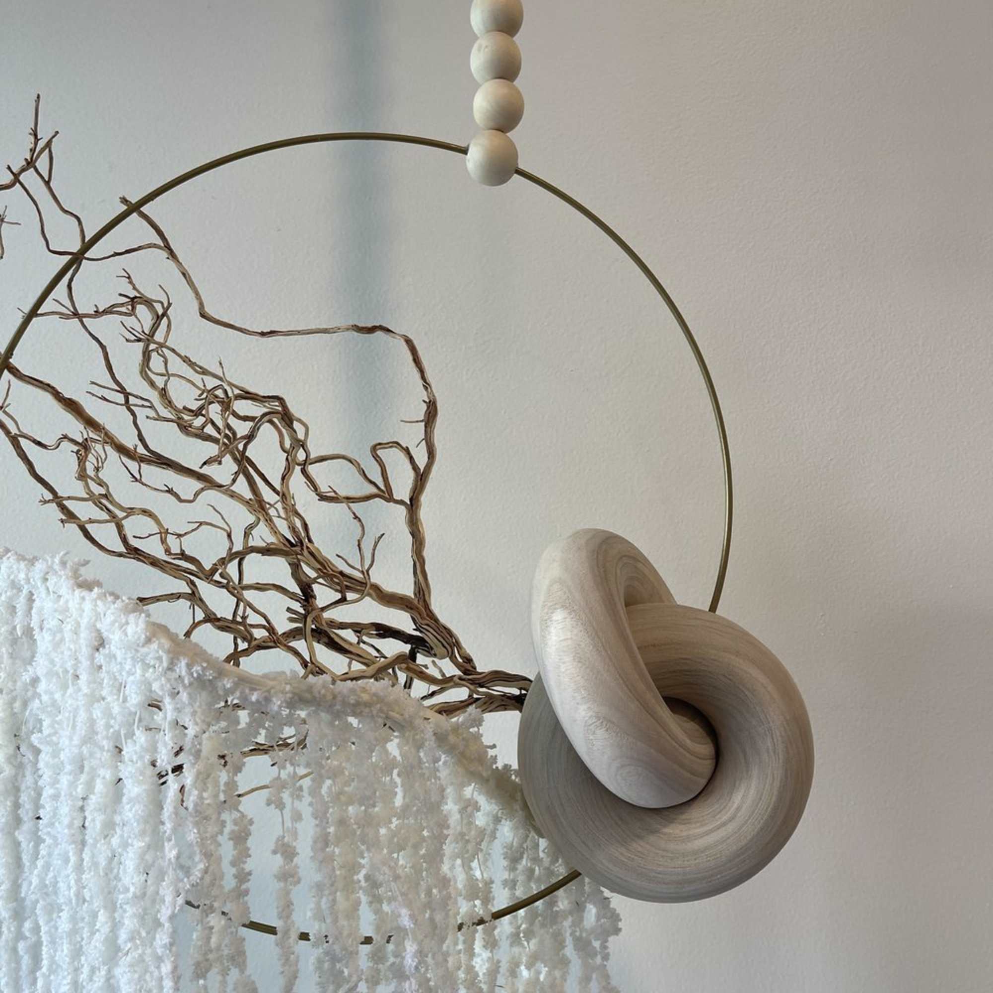 Neutral-toned hanging decor with a metal hoop, wood beads, and dried branches