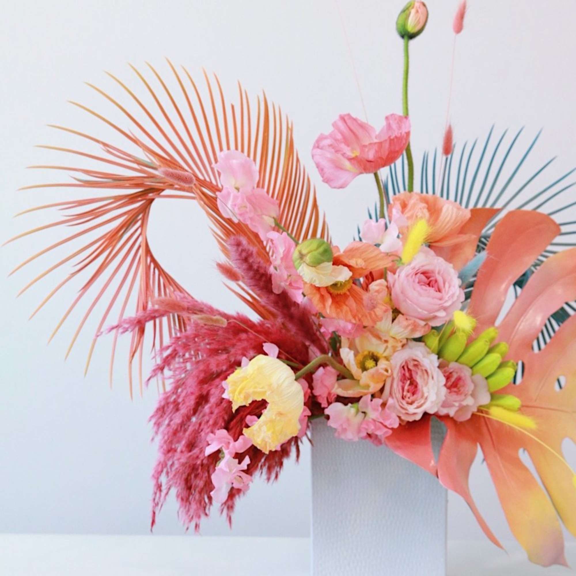 Colorful floral arrangement in a white vase with pink and peach blooms