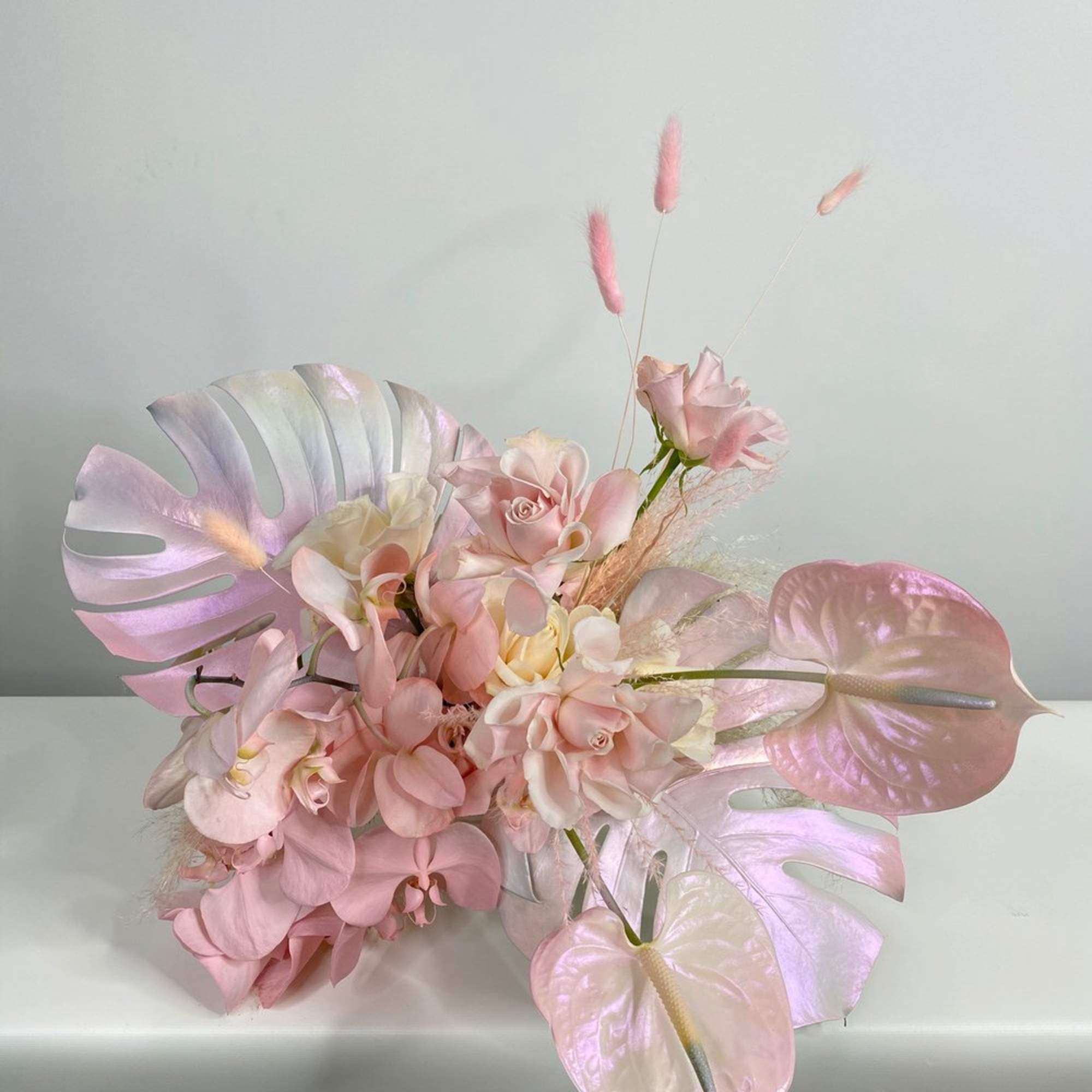 Pink floral arrangement with orchids and glossy tropical leaves