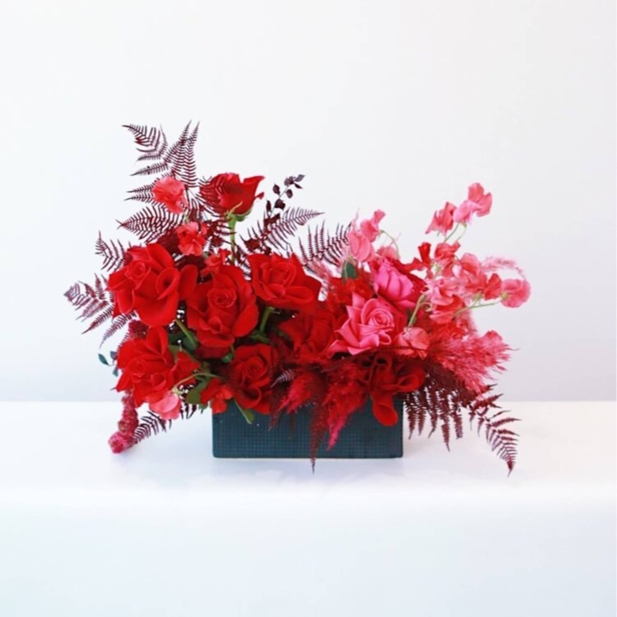 Red and pink rose arrangement in a rectangular black container